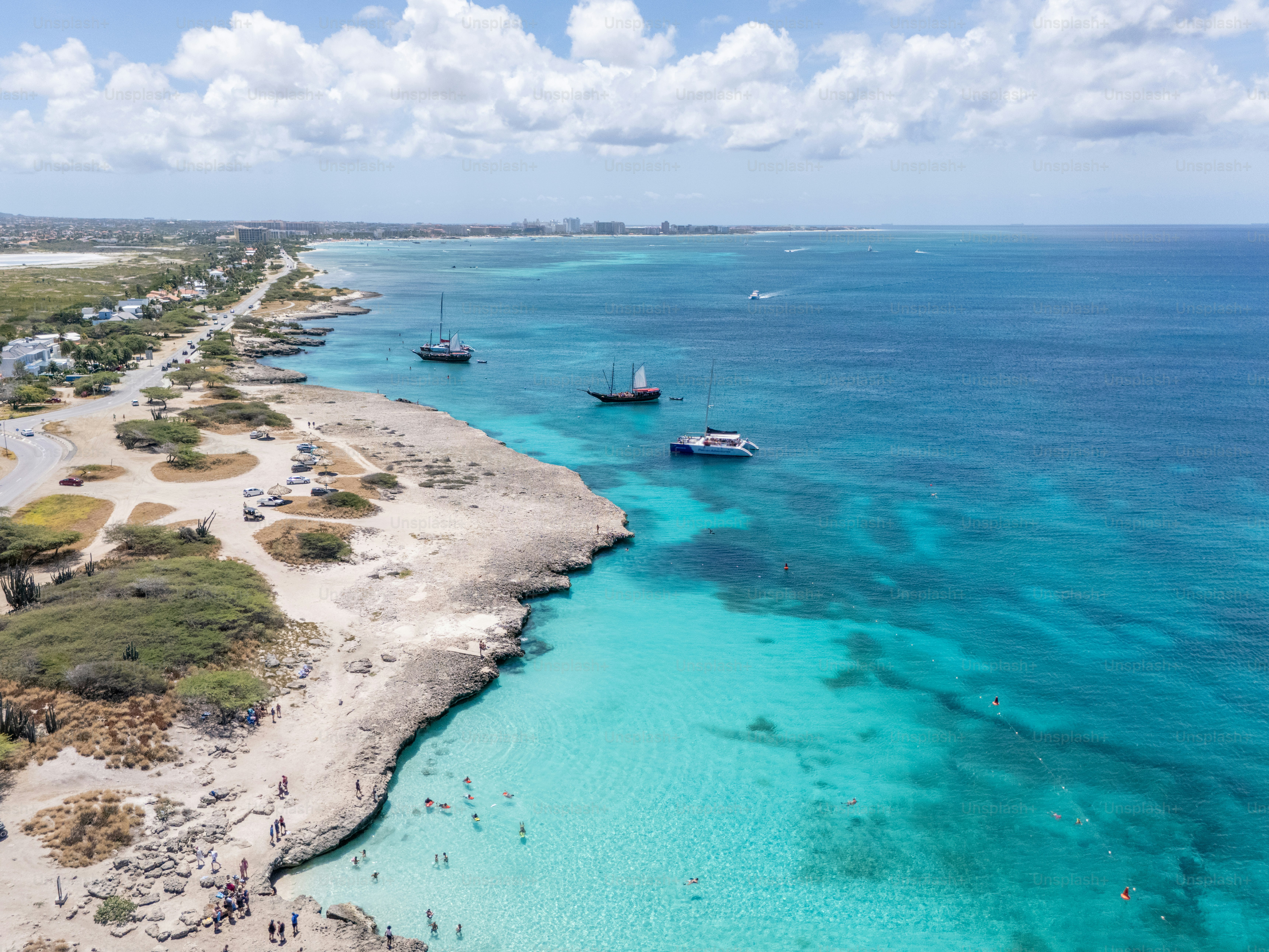 Foto aérea impressionante da costa rochosa com mar azul claro e barcos ancorados. Estrada costeira sinuosa ao longo da costa. Cenário de praia idílico para entusiastas de viagens e turismo.