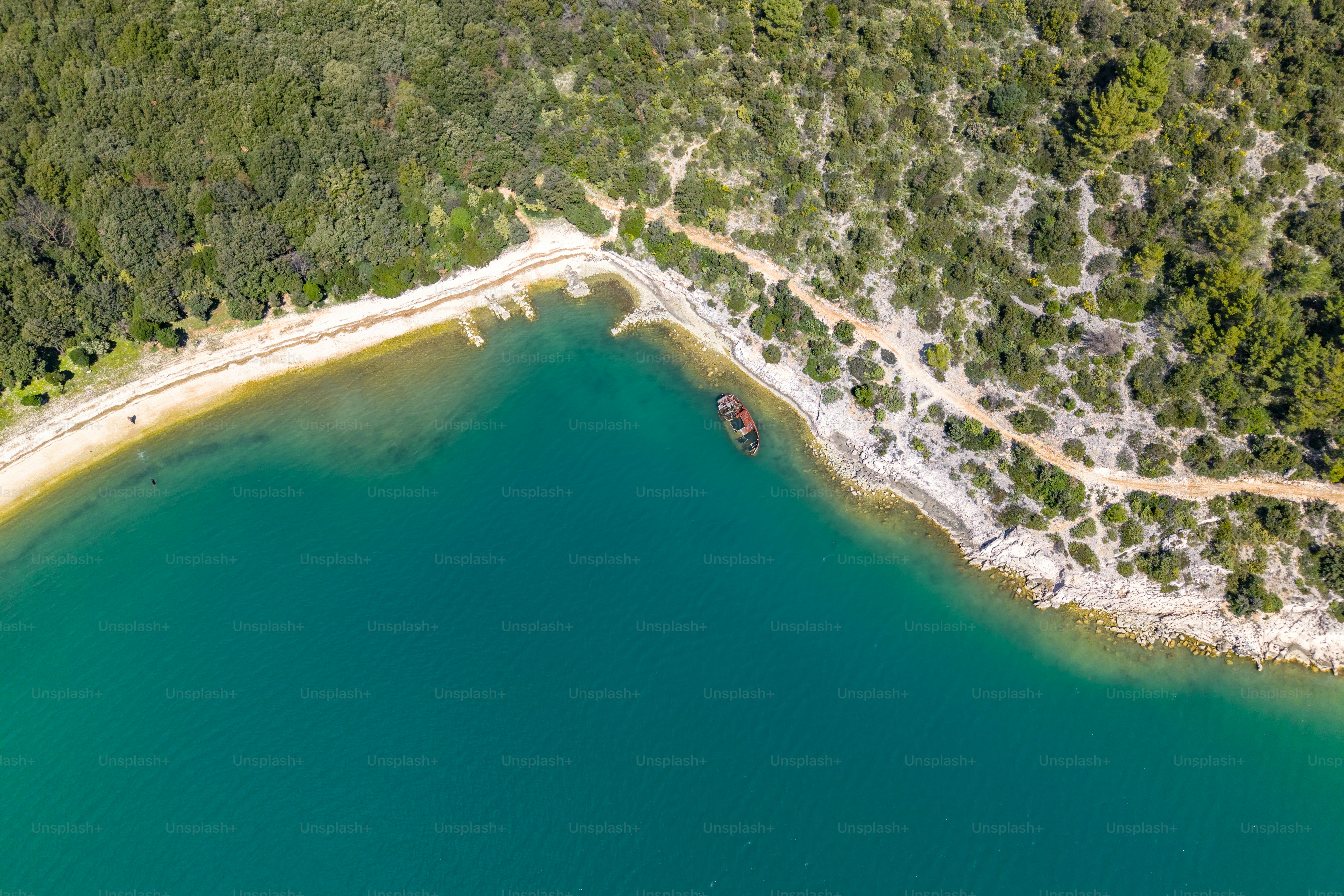 Aerial view of a sea ​​bay and an old sunken ship near the shore. Rakalj, Croatia