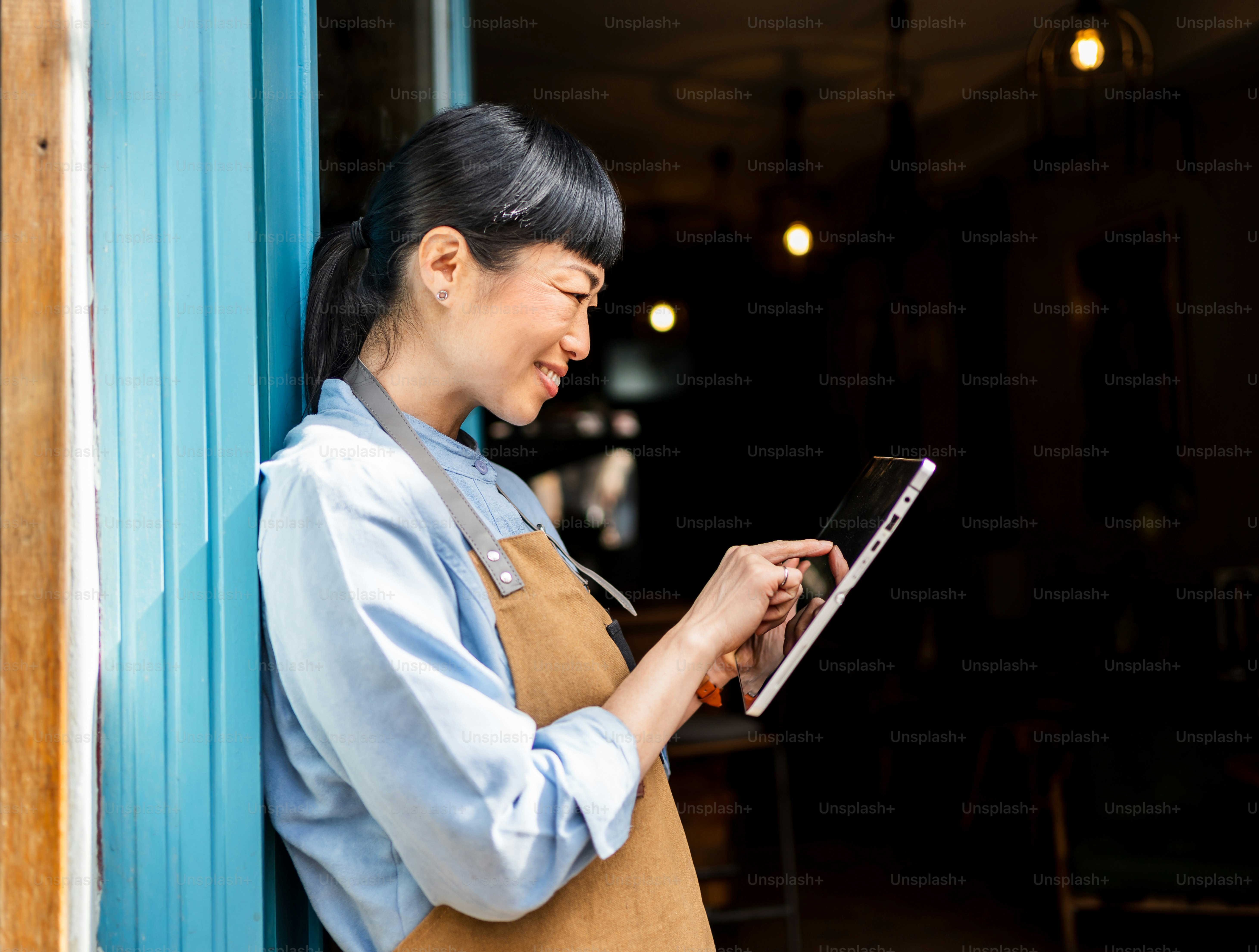 アジア系女性起業家がカフェでタブレットを使用