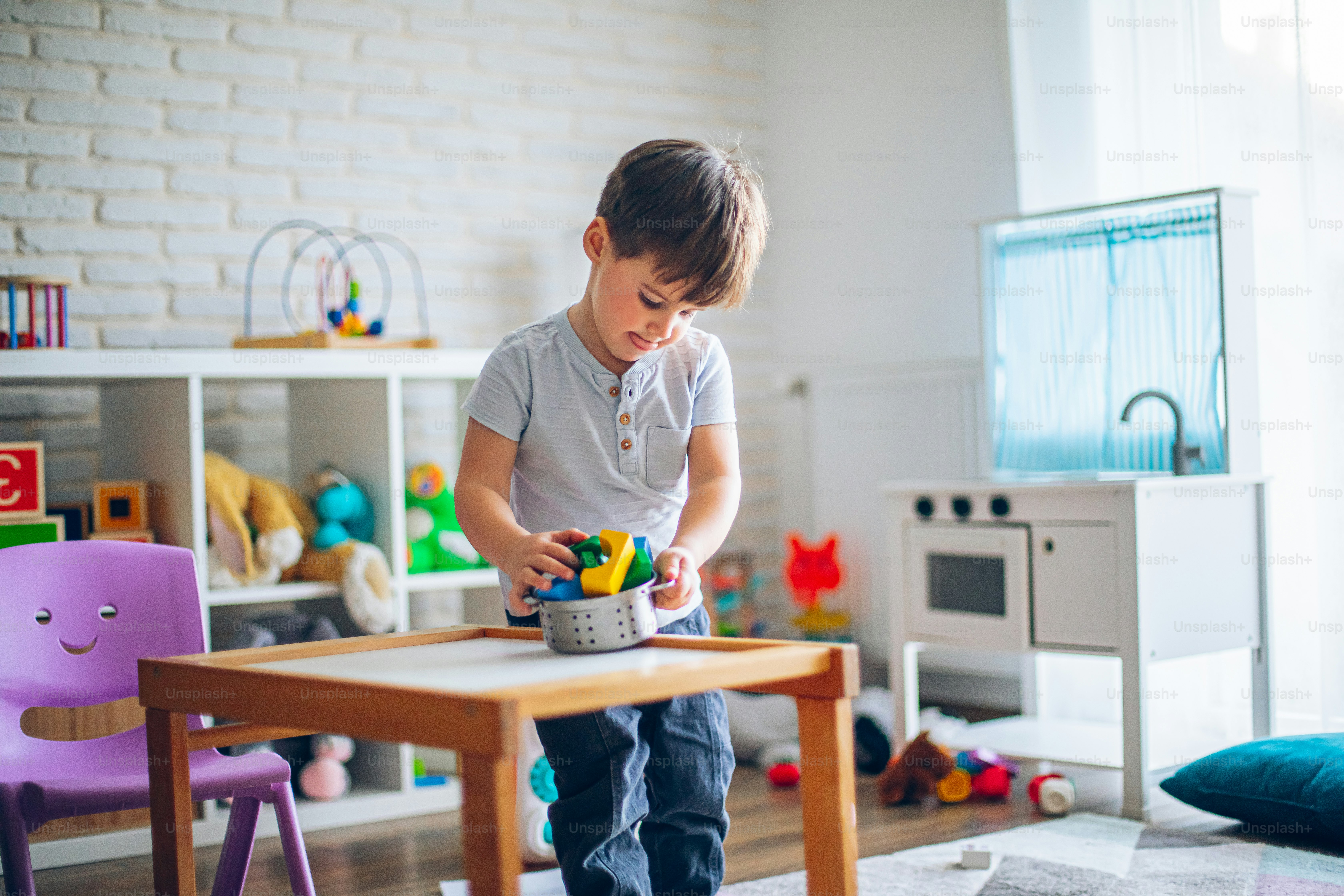Little happy boy playing with toys in his room, makes food from toys