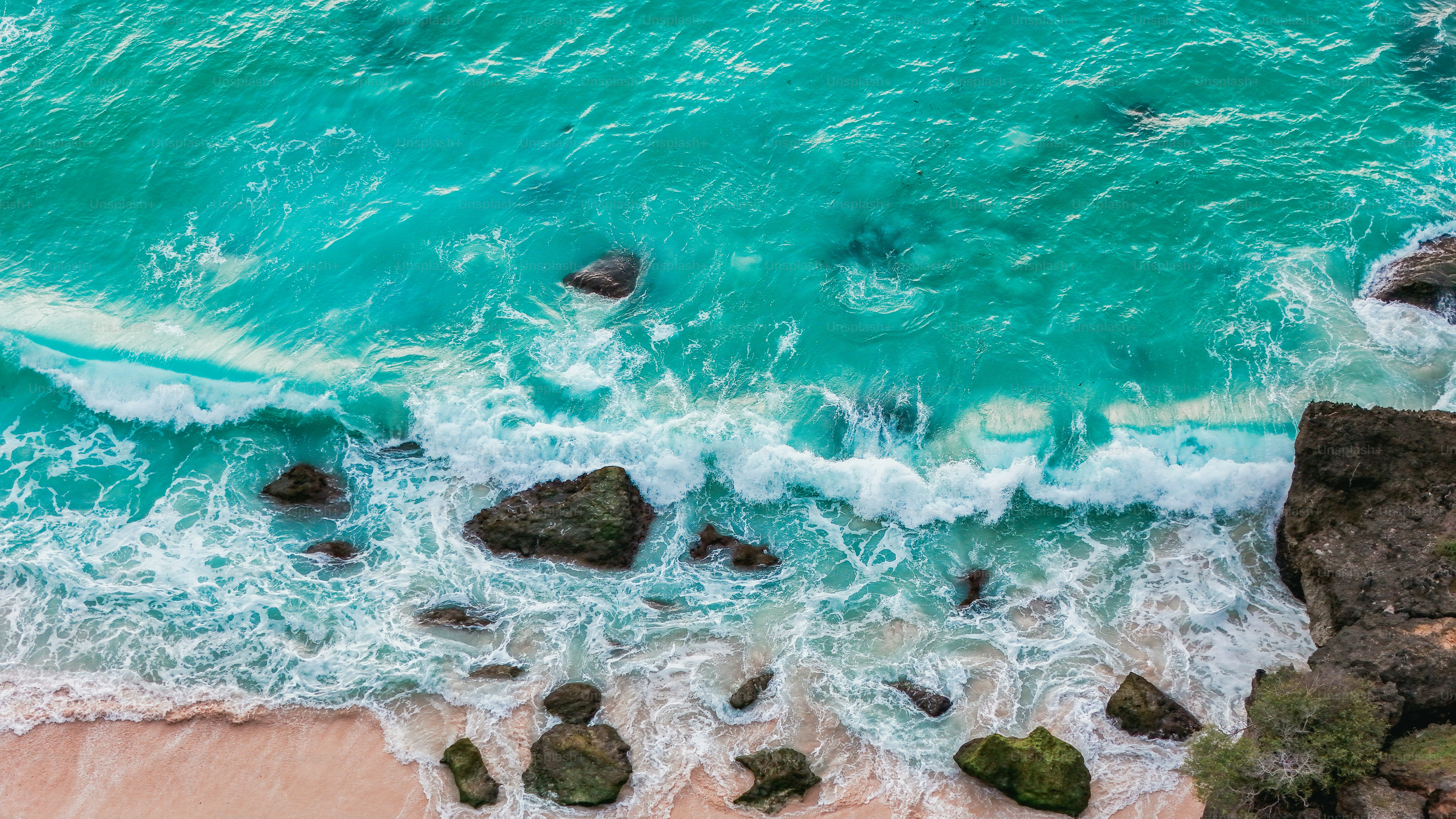 Aerial view of turquoise waves washing over white sand on a tropical ...