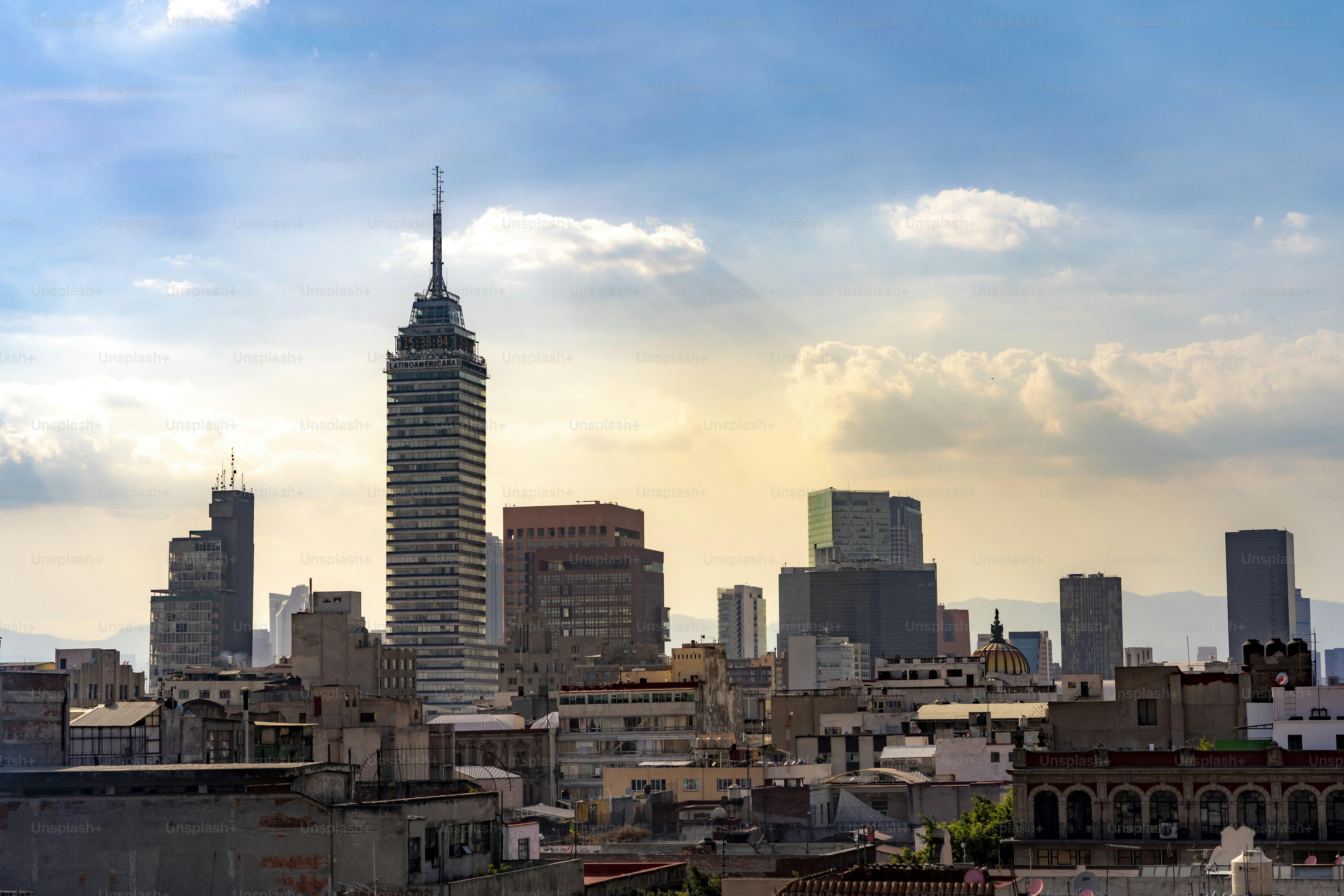 The Mexico City skyline with Torre Latinoamericana and modern skyscrapers, captured during sunset with dramatic clouds and golden light.