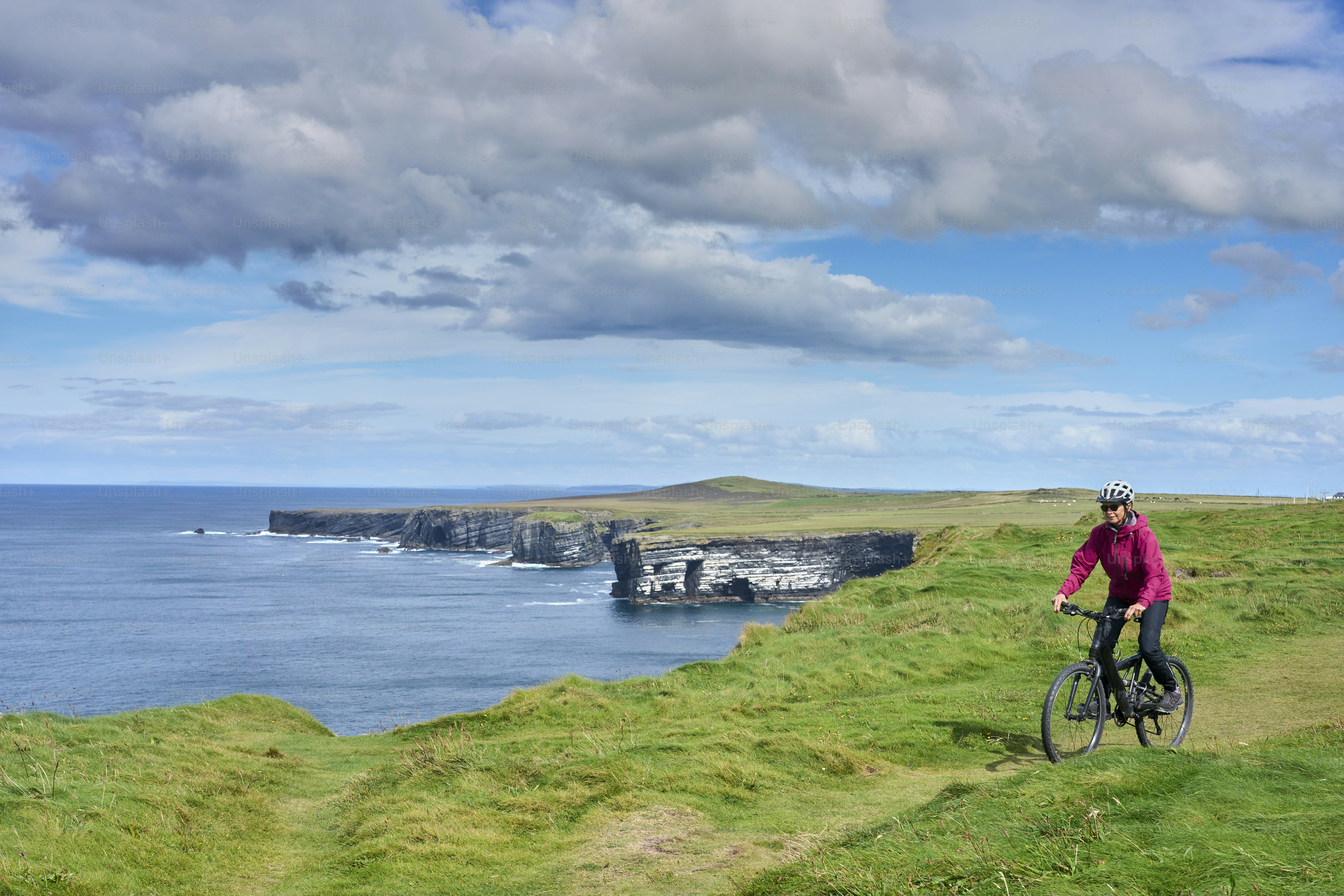 nice senior woman on mountain bike, cycling on the cliffs of Dunmore Head near Kilballyowen , County Limerick in the southwestern part of the Republik of Ireland