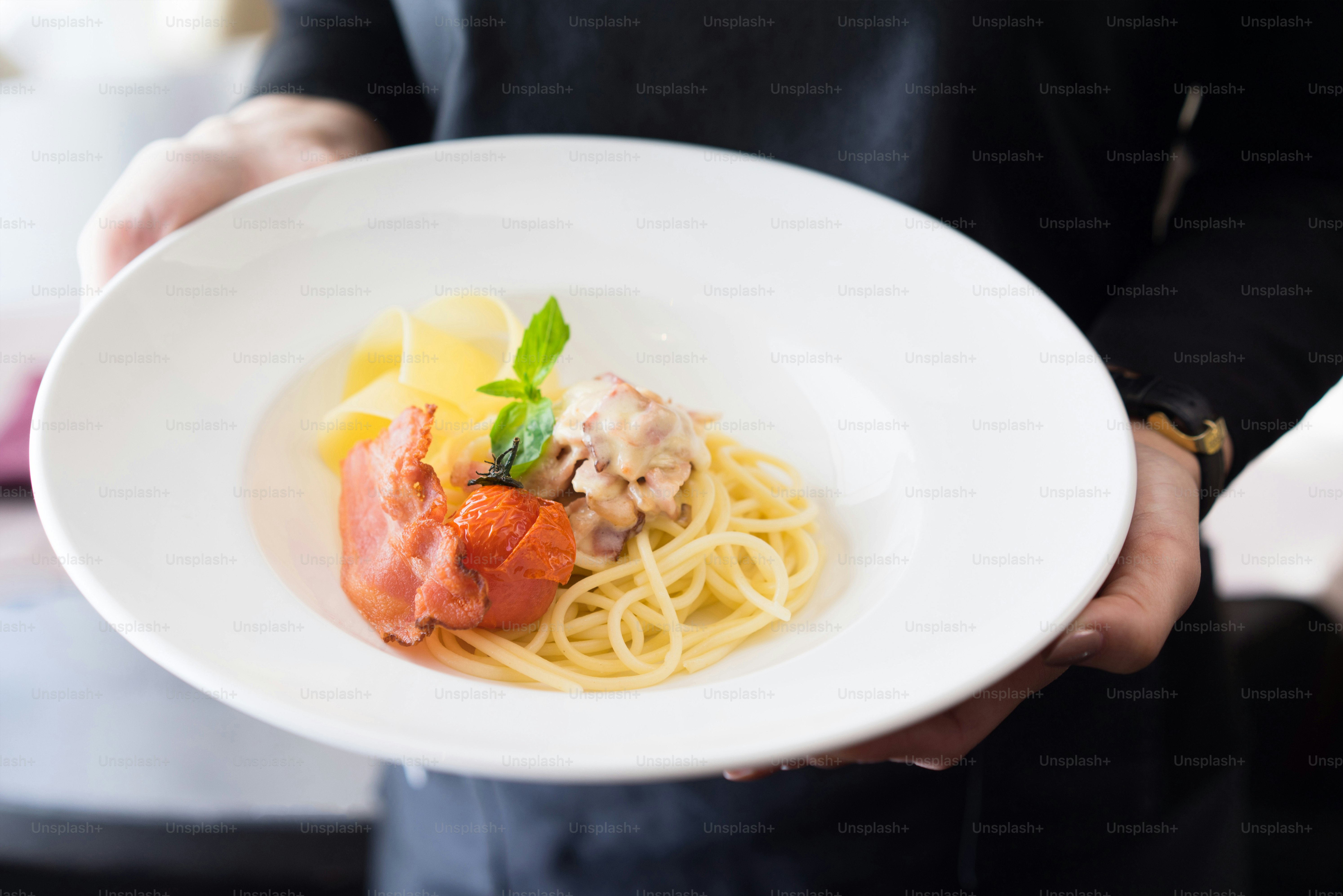 Close-Up of Gourmet  Bacon Pasta Dish on a Chefs or waitress hands