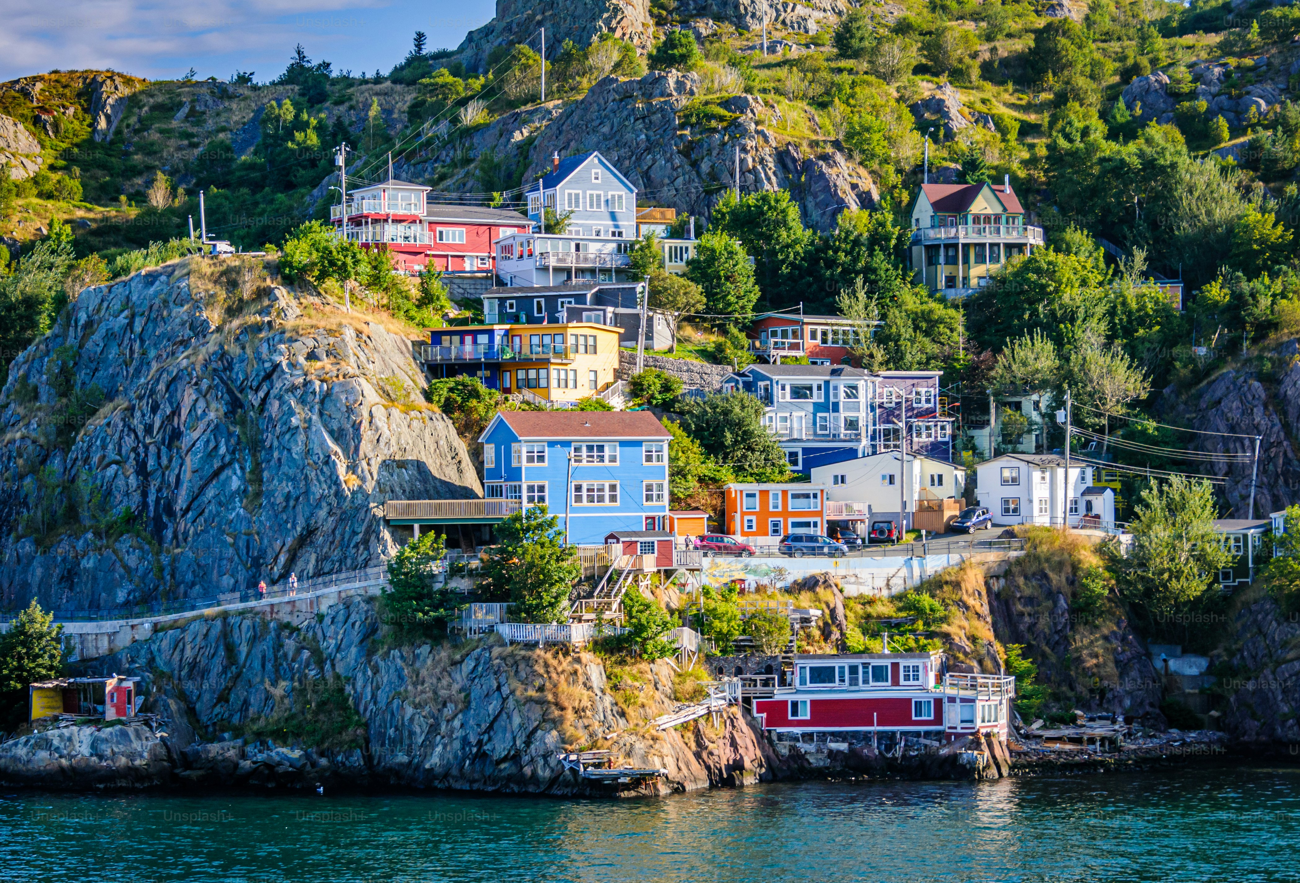 Morgenlicht erhellt farbenfrohe Häuser am felsigen Hang von The Narrows, einer Bucht, die in den St. John's Harbor in Neufundland, Kanada, mündet