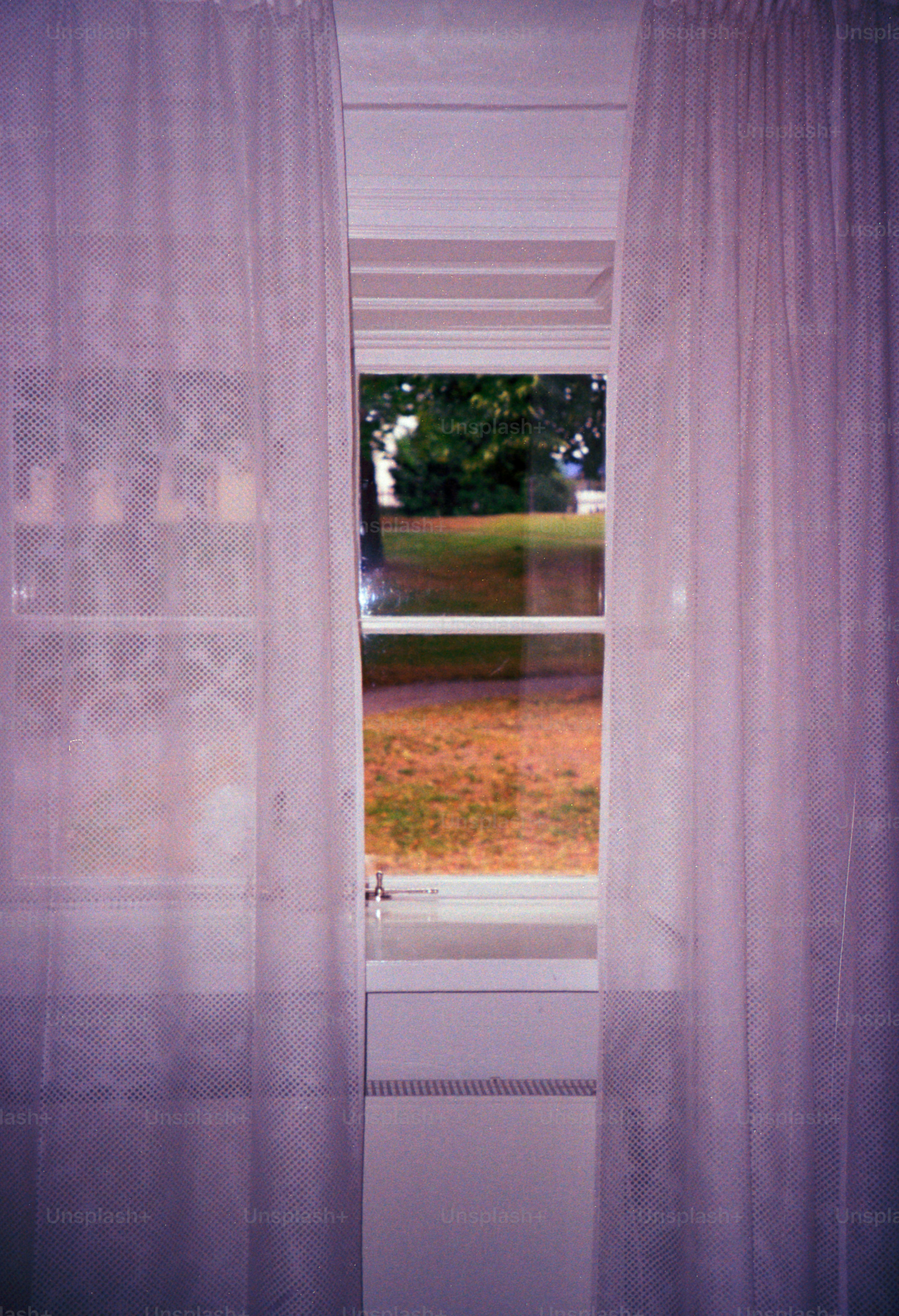 Tirai membingkai jendela terbuka dengan pemandangan.