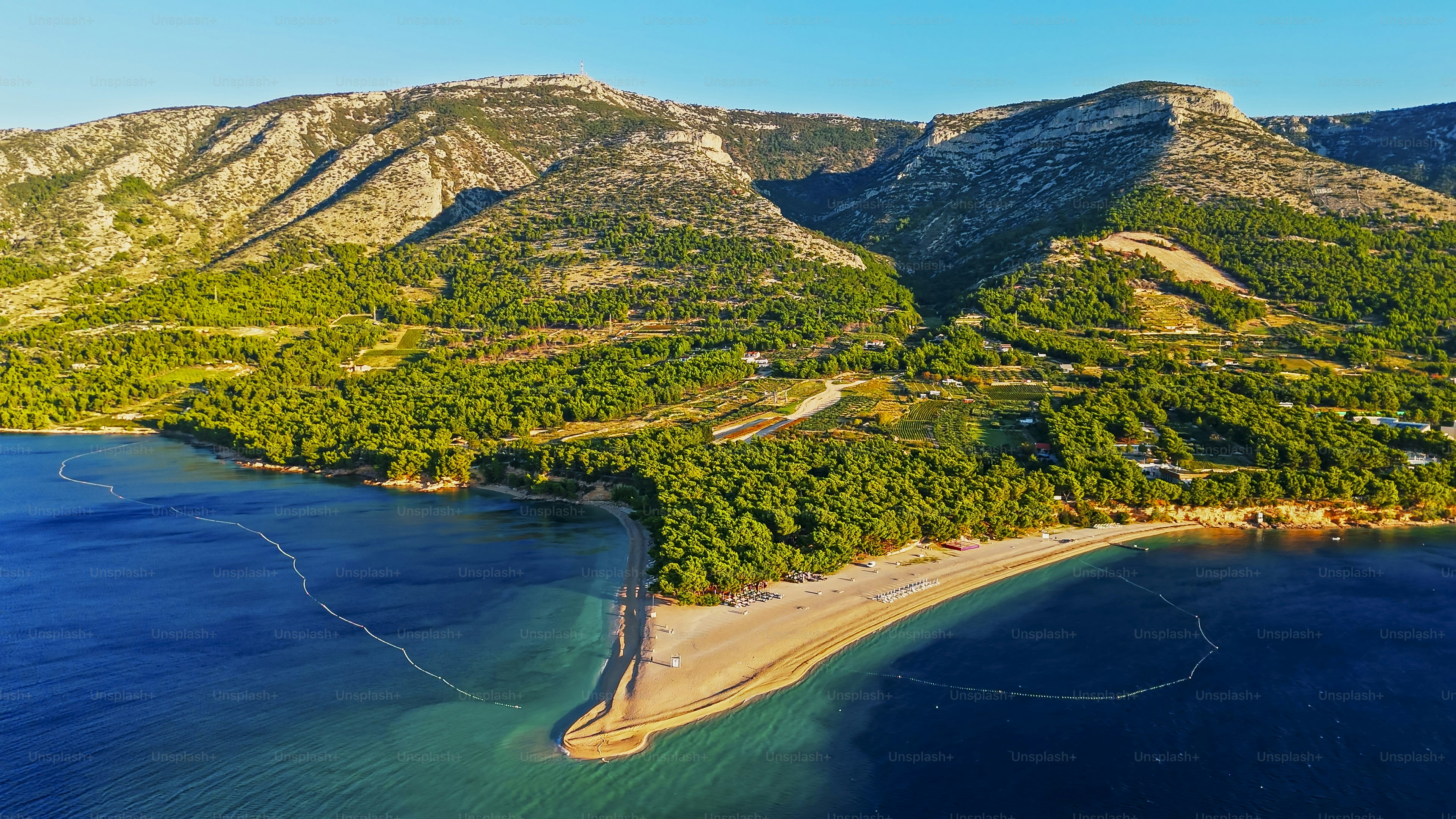 La playa de Zlatni Rat en Bol al amanecer cuenta con arenas doradas, tranquilas aguas del Adriático y un exuberante telón de fondo montañoso, que ofrece un entorno natural tranquilo