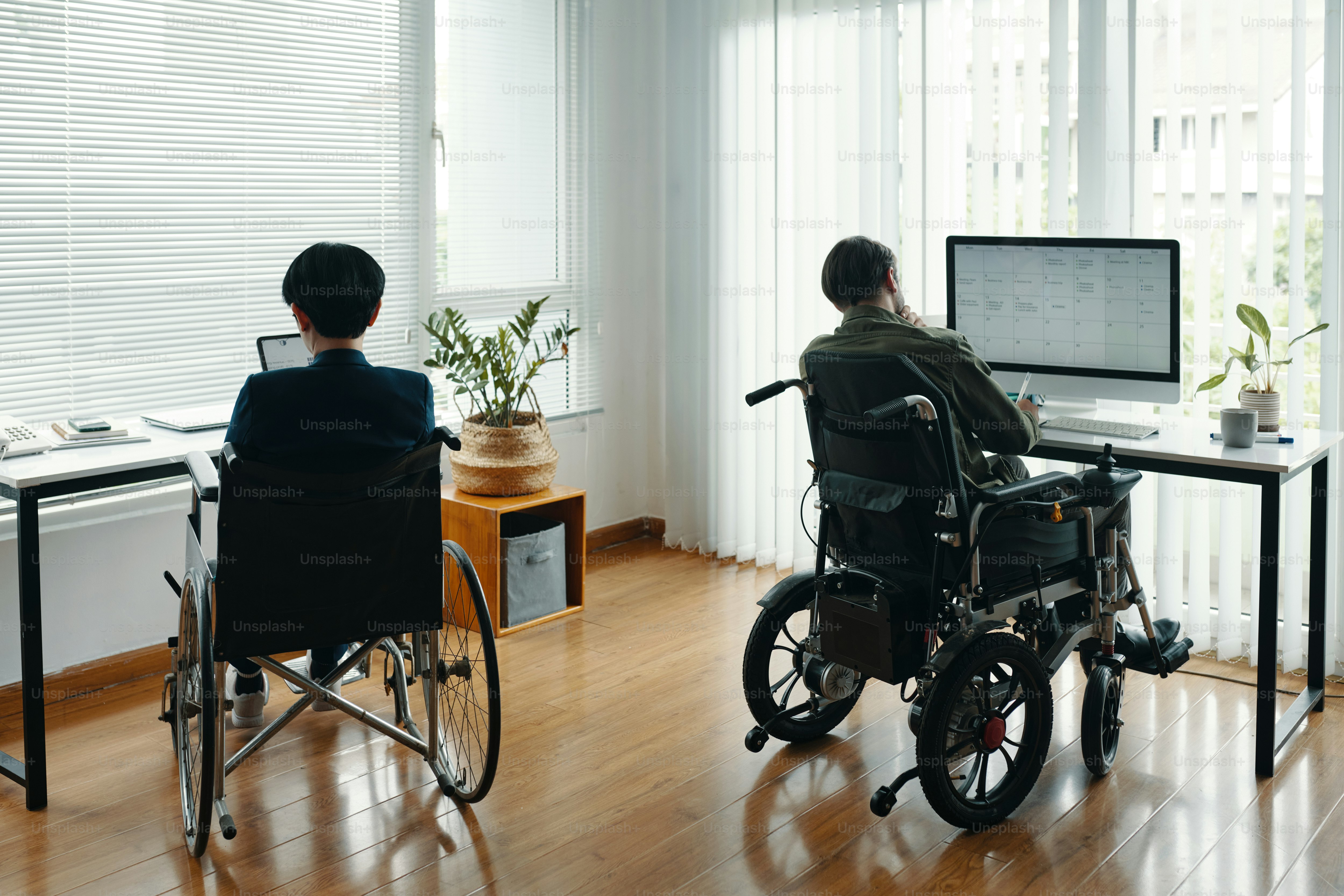 Rear view of business people with disability working on computers in ...