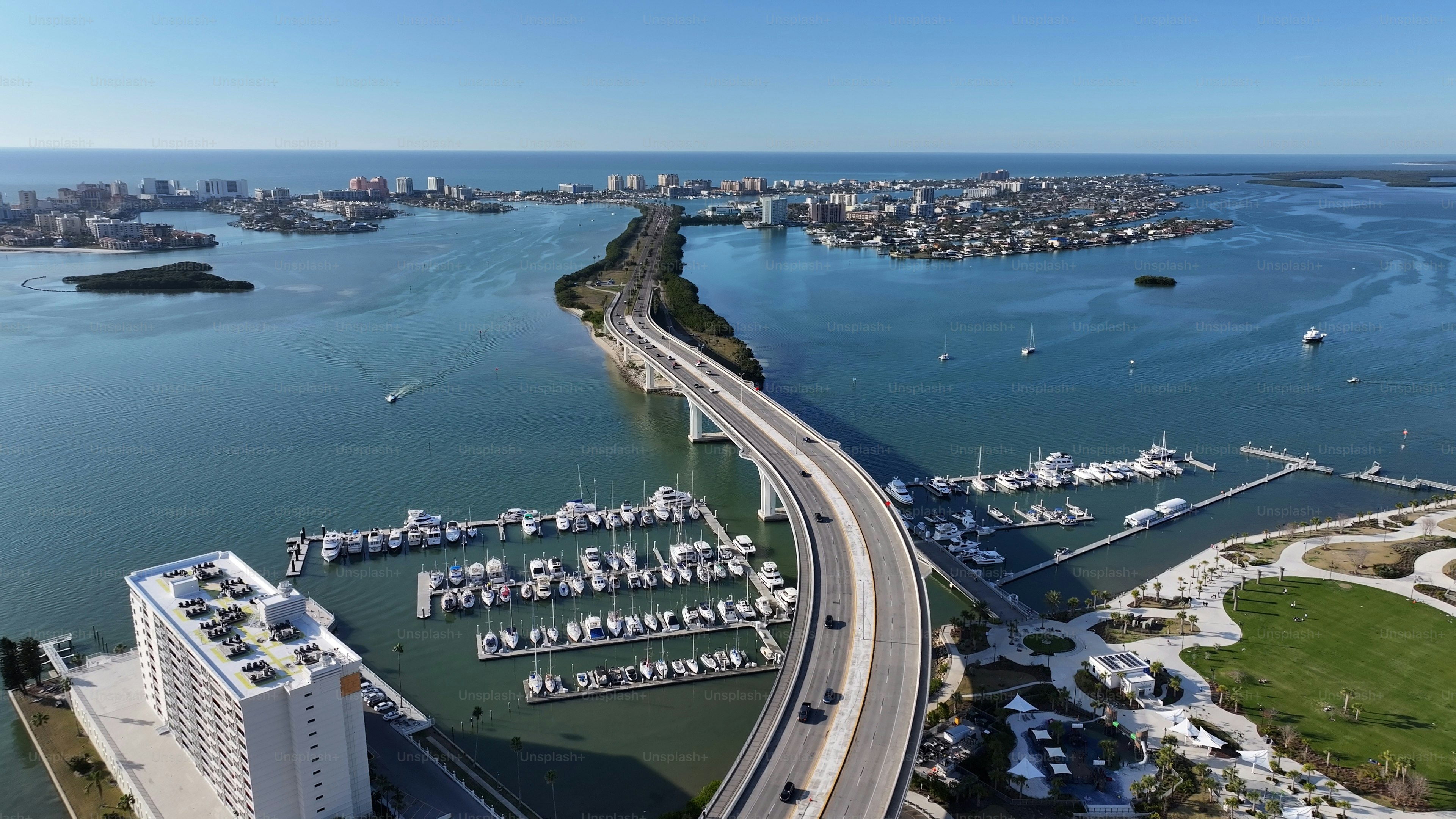 An aerial view of a bridge spanning water with marinas and coastal buildings