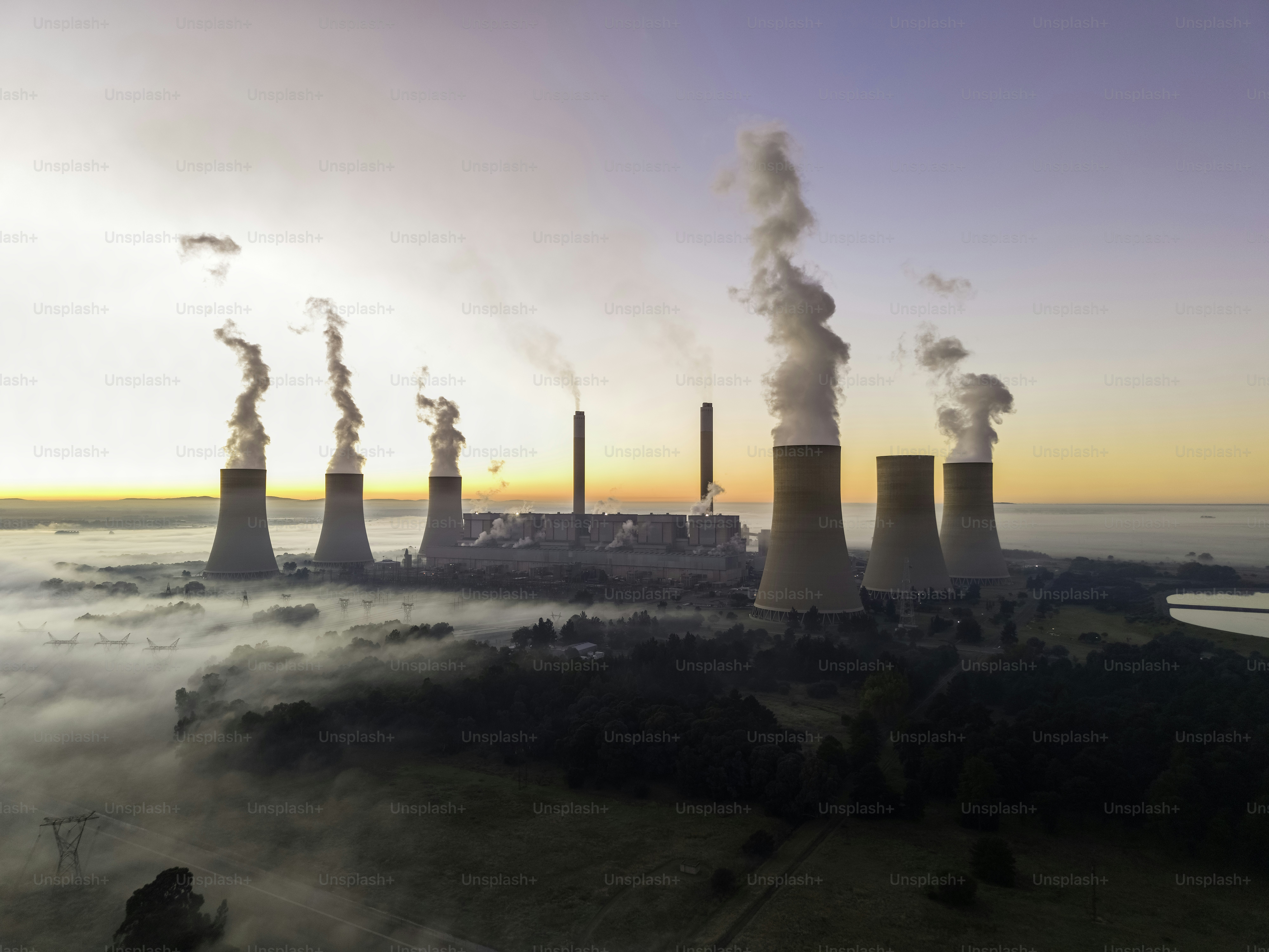 Central eléctrica de Lethabo vista al amanecer con el smog y la niebla sobre el campo y el vapor que se eleva desde las torres de enfriamiento