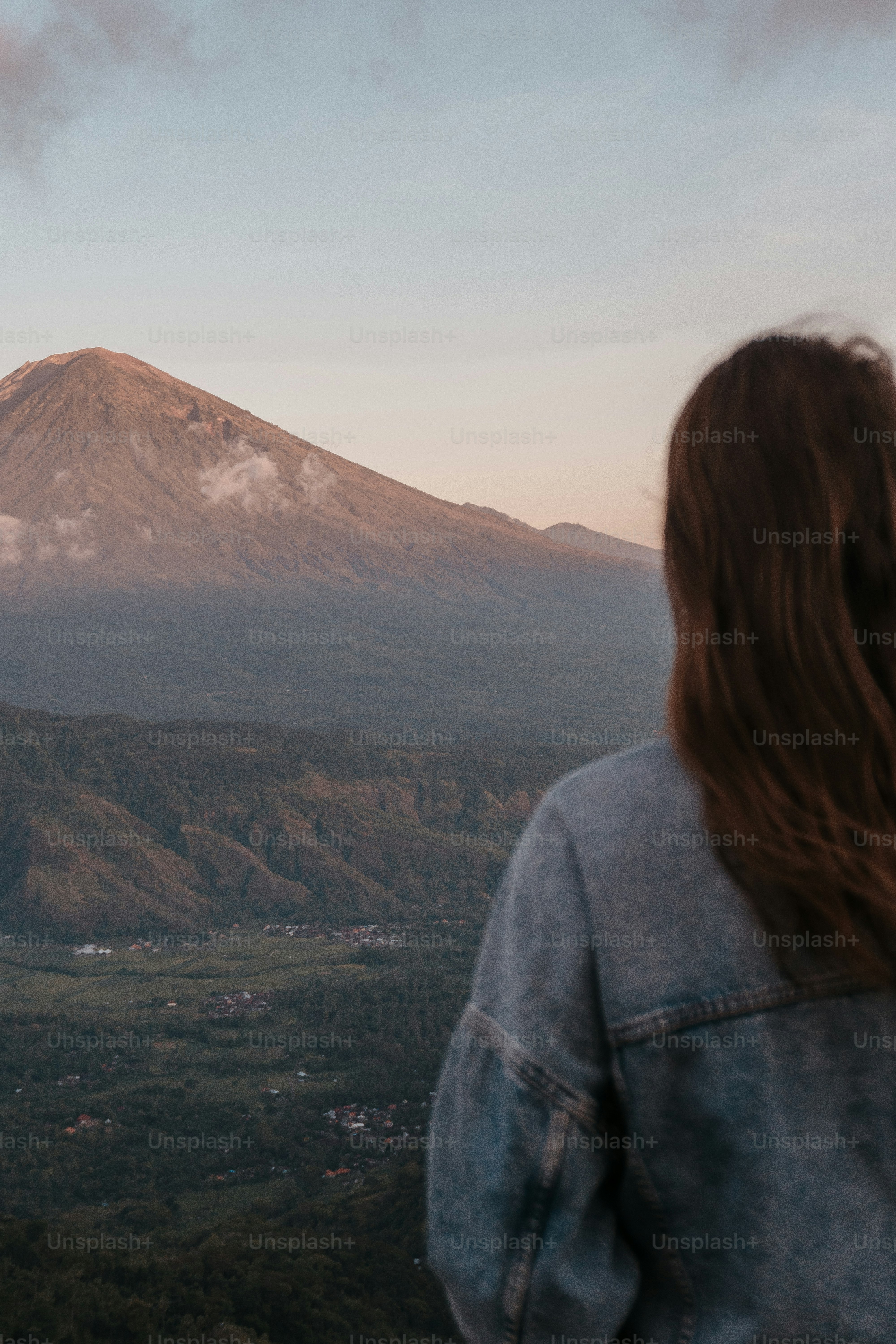 Wanita menatap pegunungan saat matahari terbenam.
