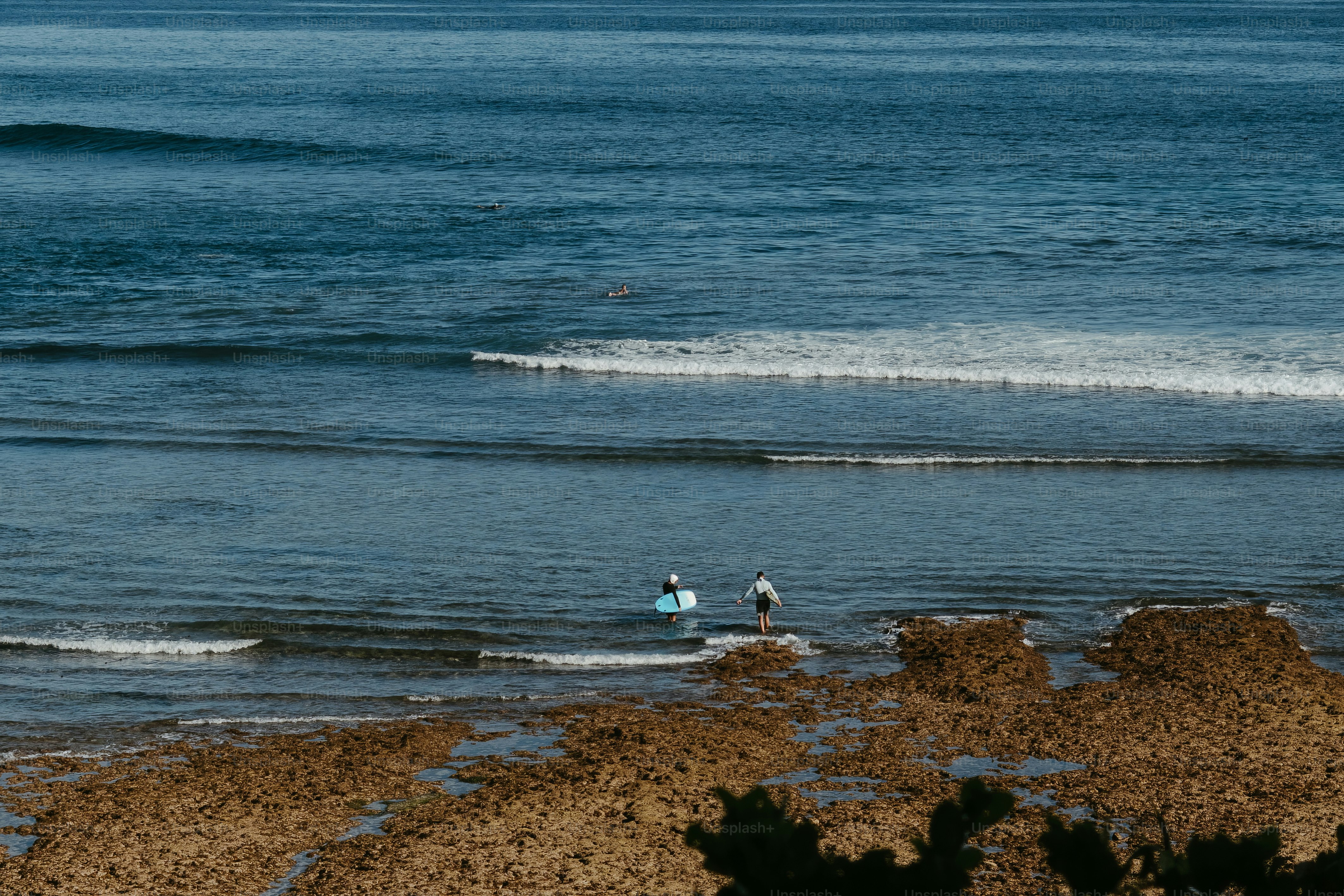Duas pessoas na água com pranchas de surf.