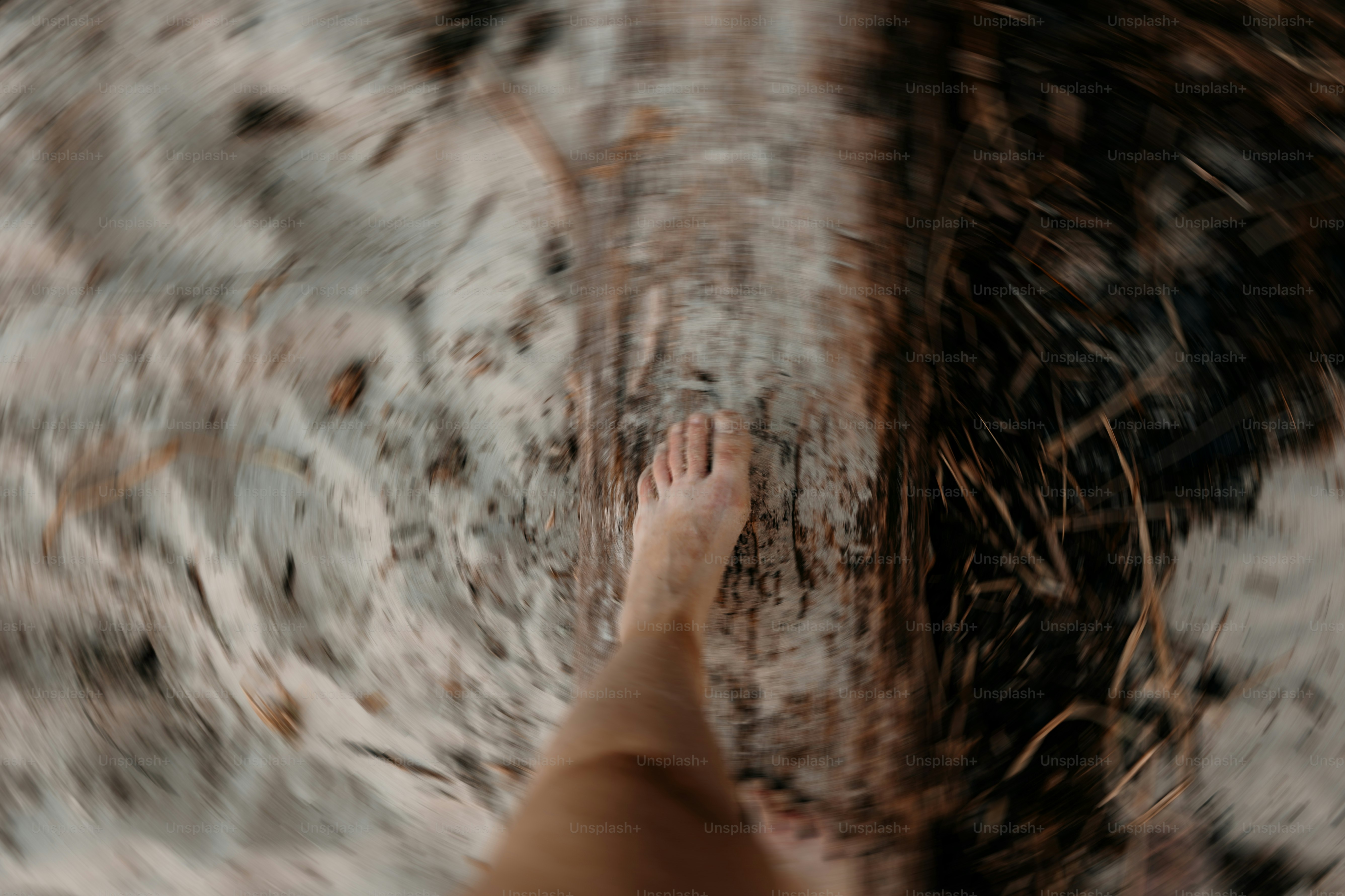 A bare foot walks over gritty sand.