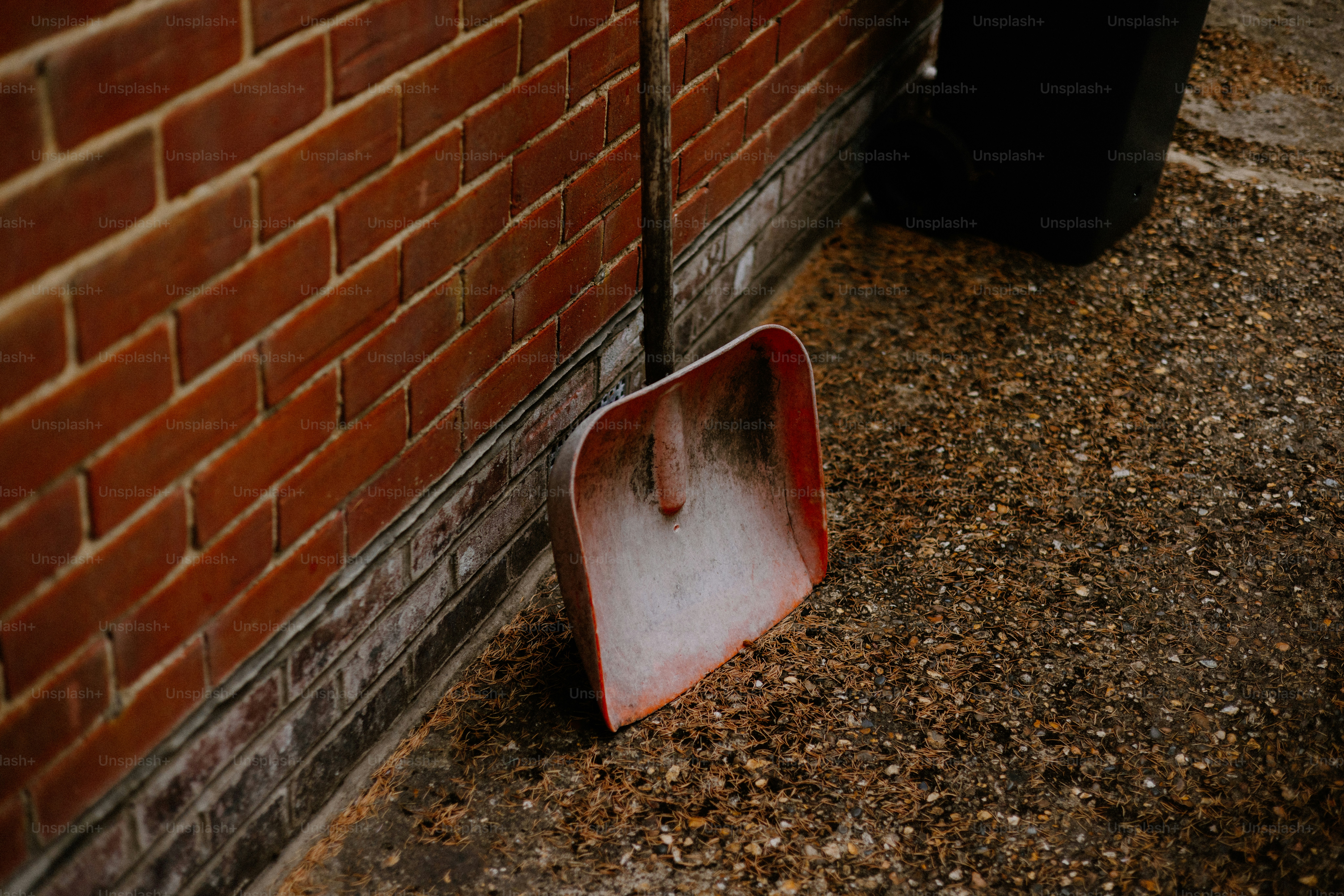A shovel leans against a brick wall.
