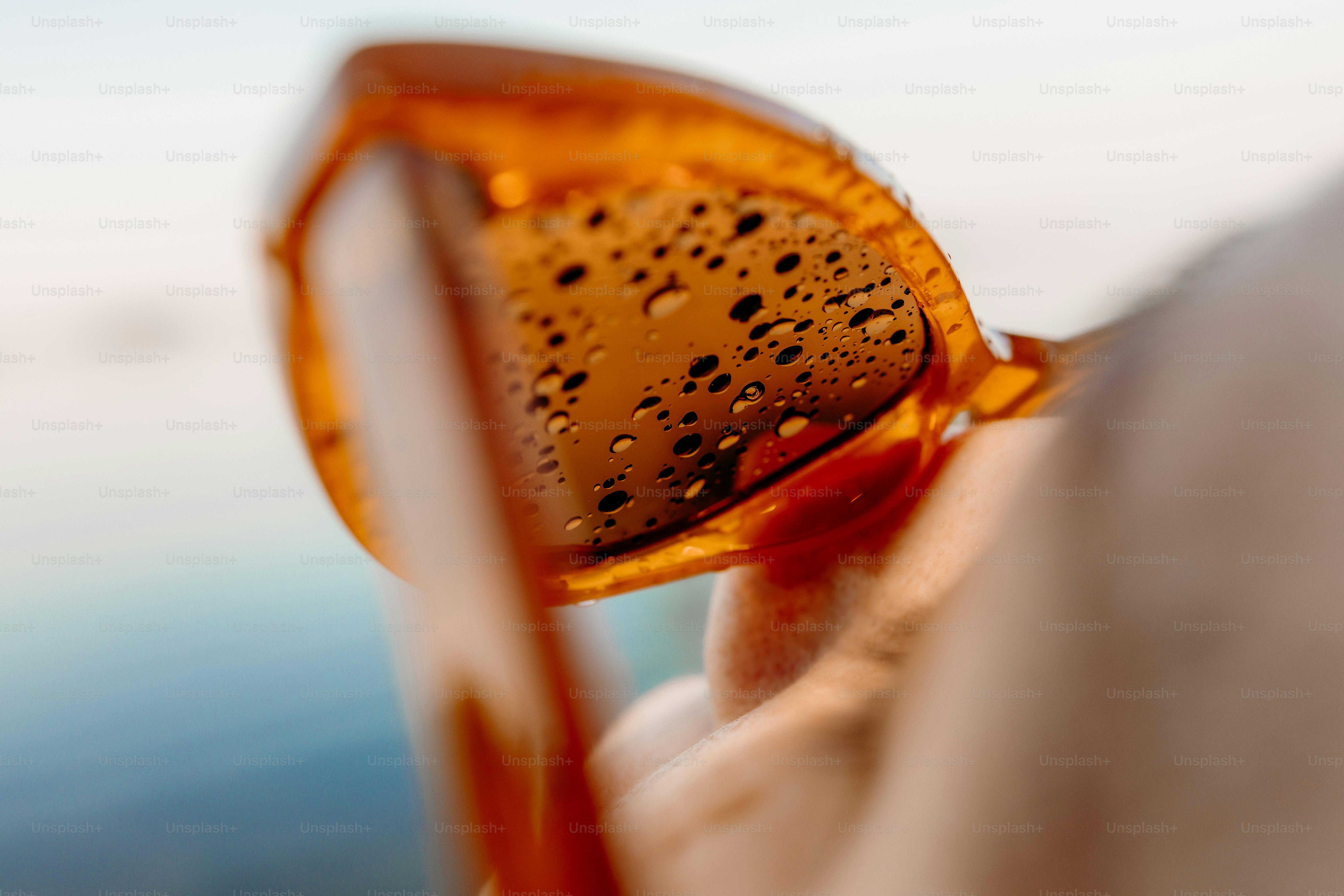 Close-up of sunglasses with water droplets on lens.