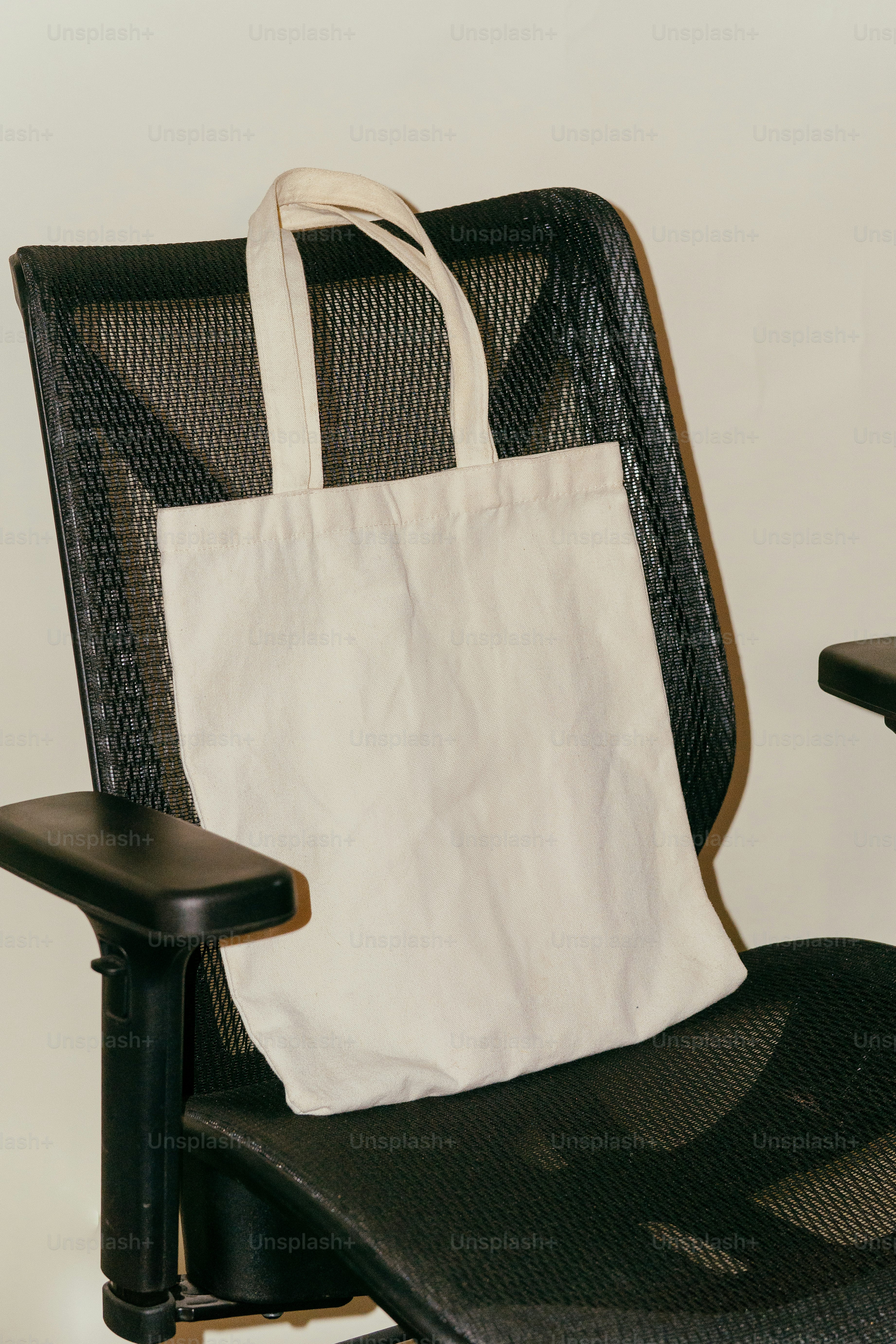 A canvas tote bag rests on an office chair. photo – Marketing Image on ...
