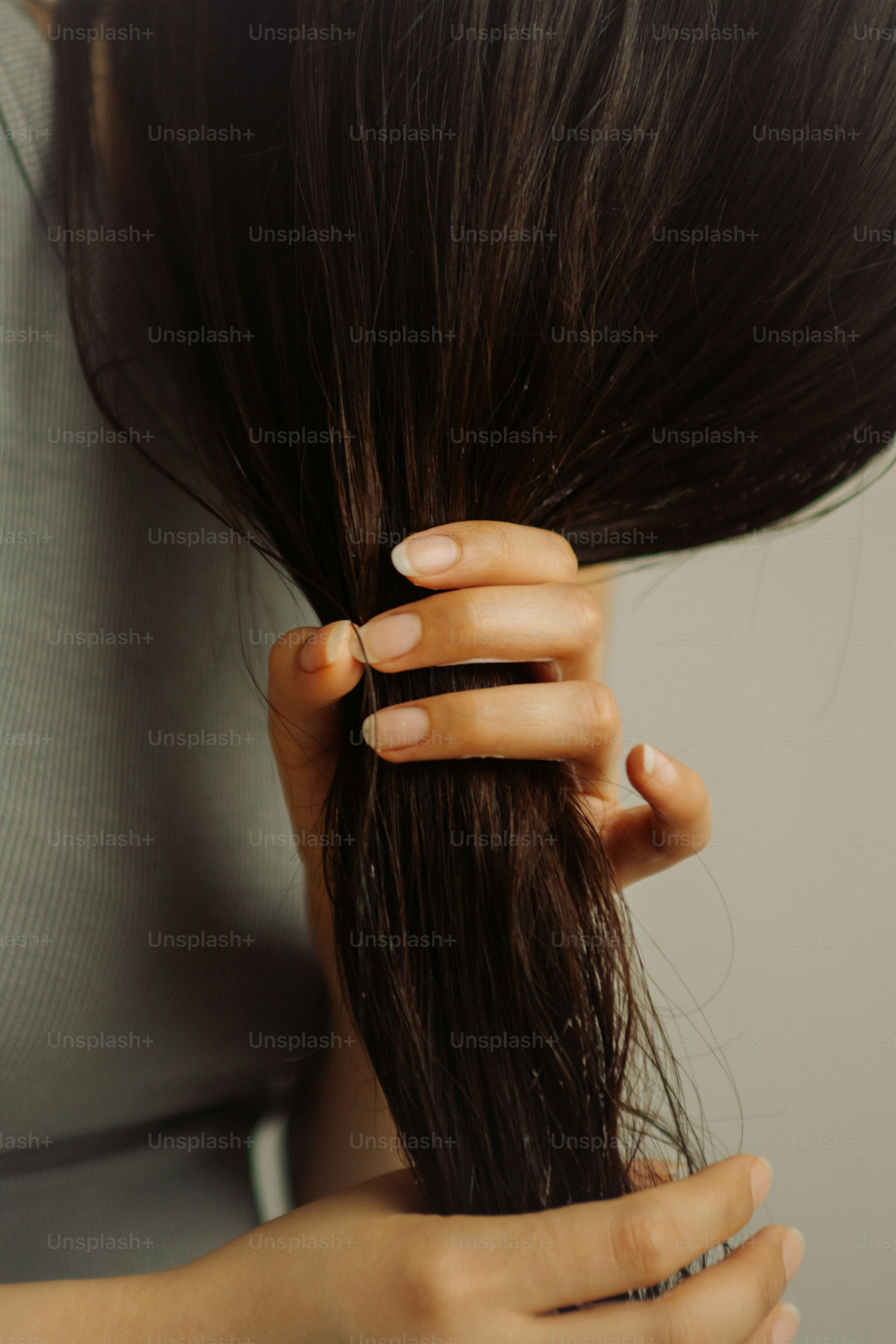 Mano sosteniendo una sección de cabello oscuro y suelto.