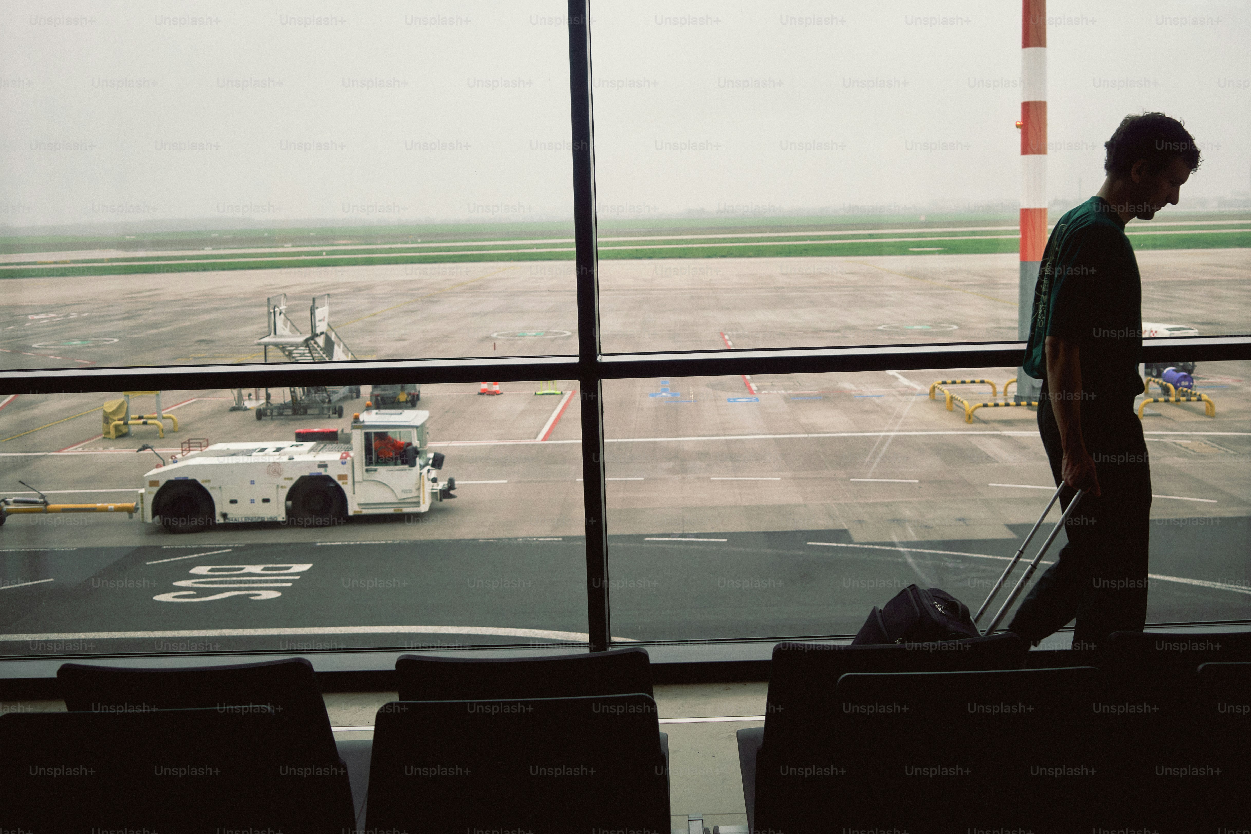 Man walking at airport with luggage by window
