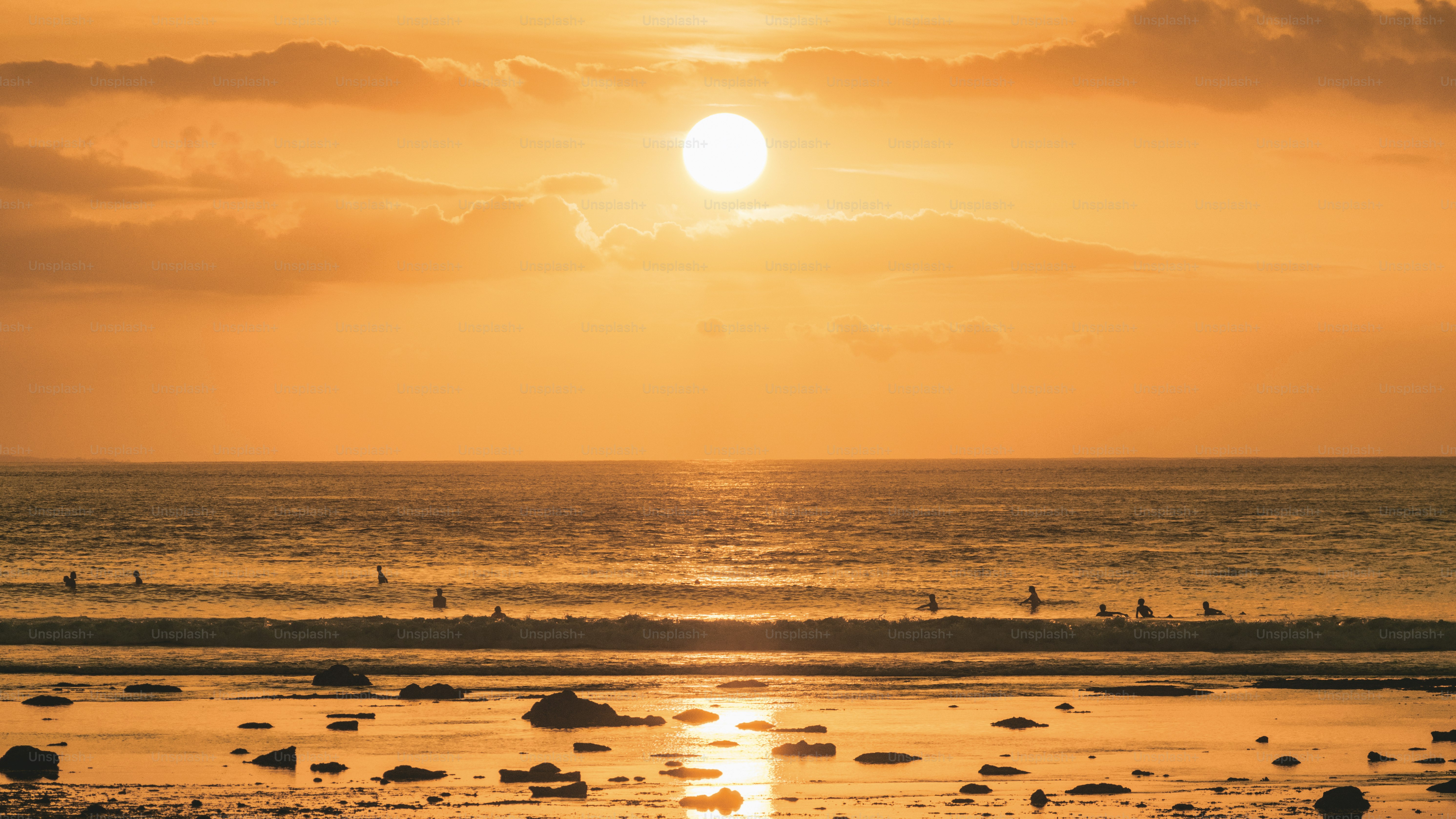 Golden sunset over the ocean with surfers. photo – Summer Image on Unsplash