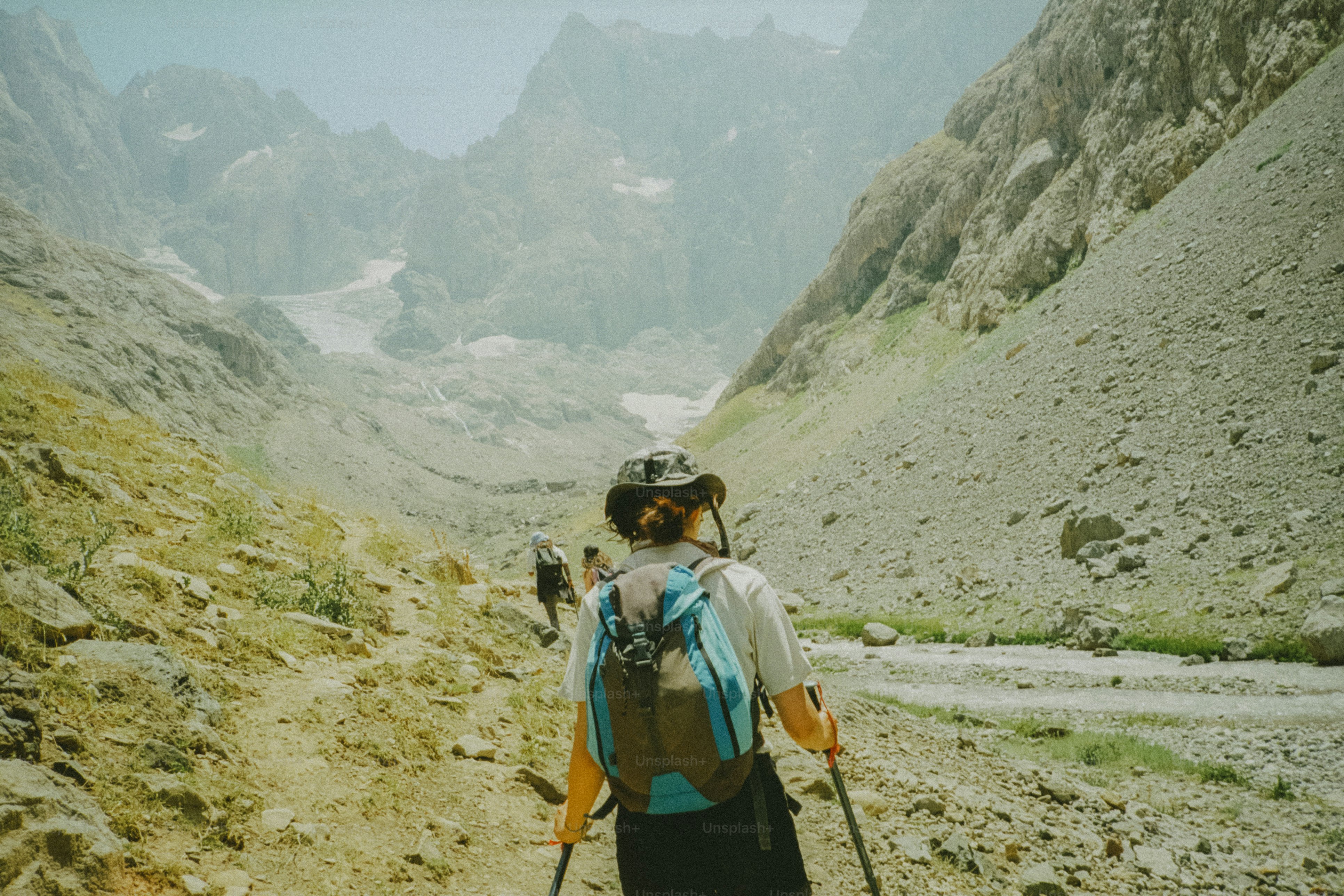 Hikers ascend a mountain trail into a valley.