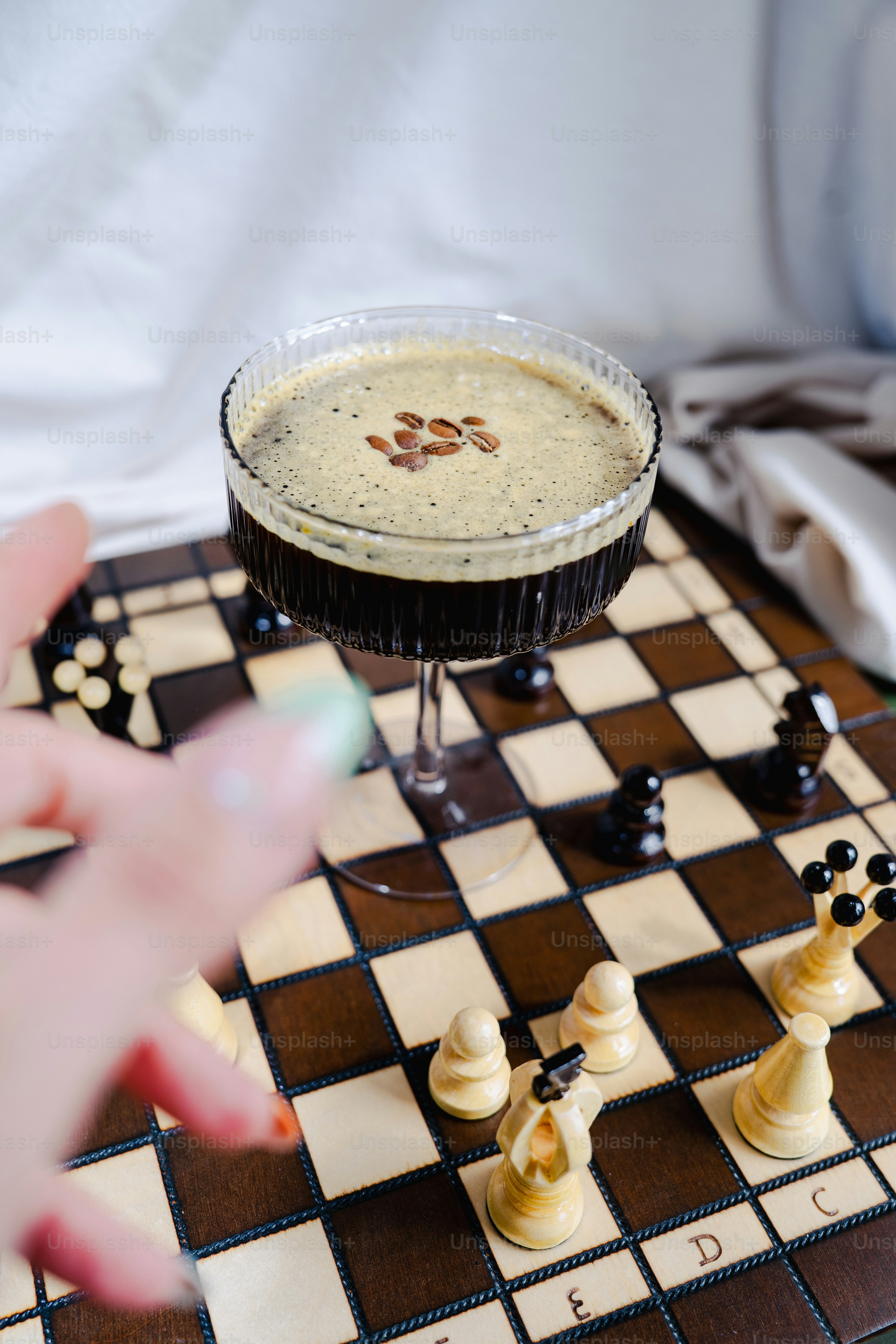 Coffee cocktail and chess pieces sit on a chessboard.