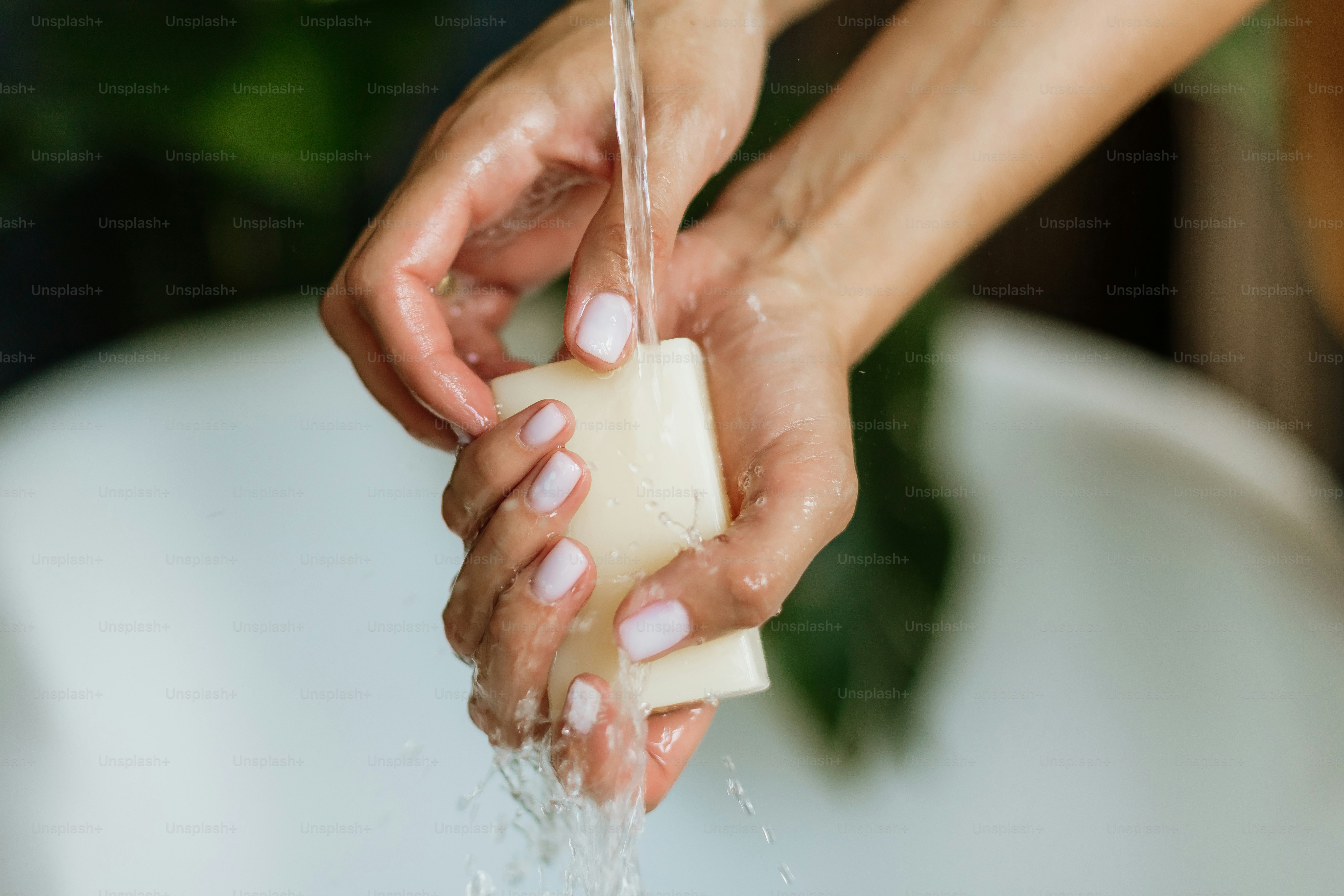 Hands washing with bar soap under running water