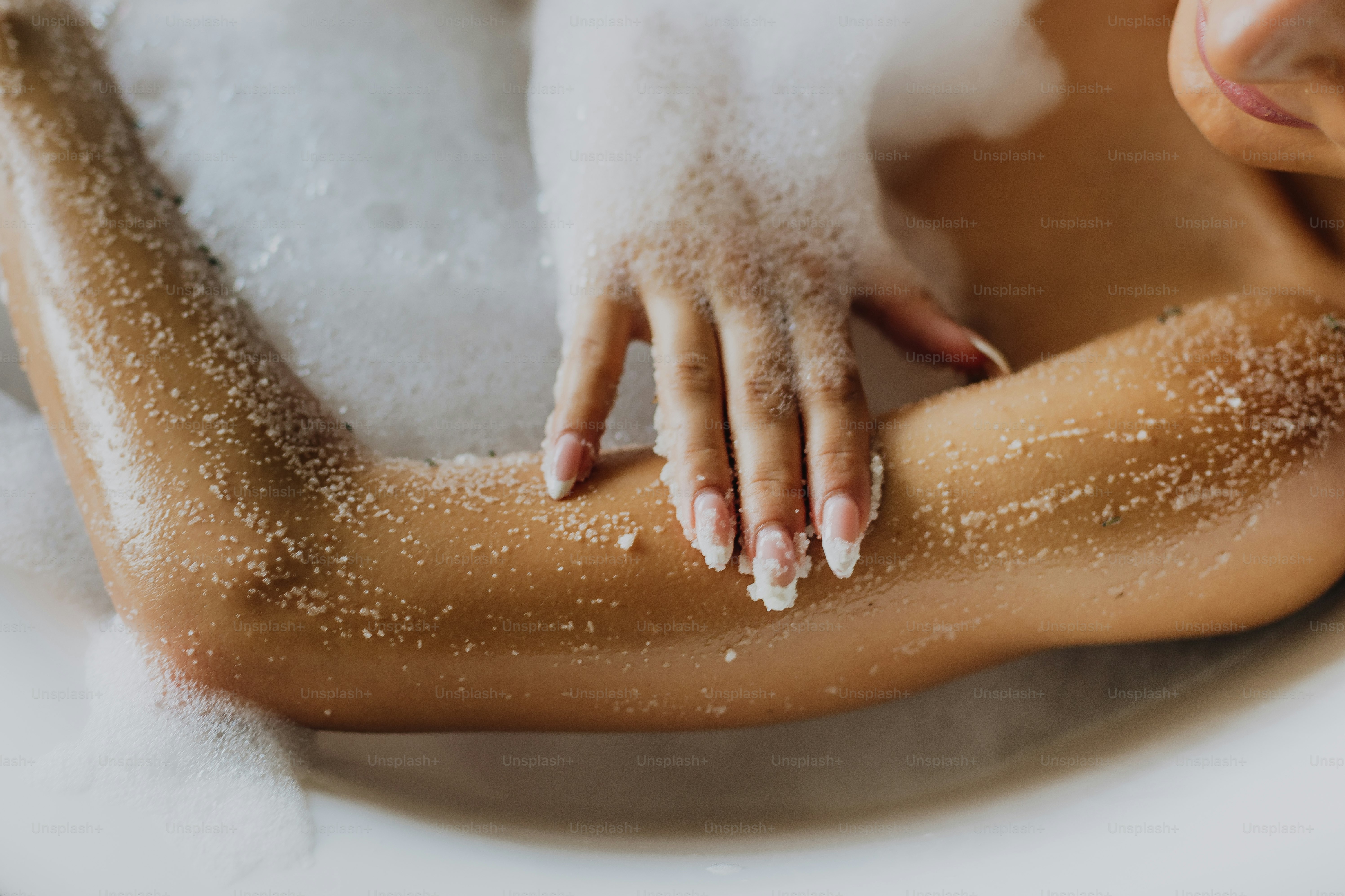 Close-up of a person's arm covered in bath salts and bubbles