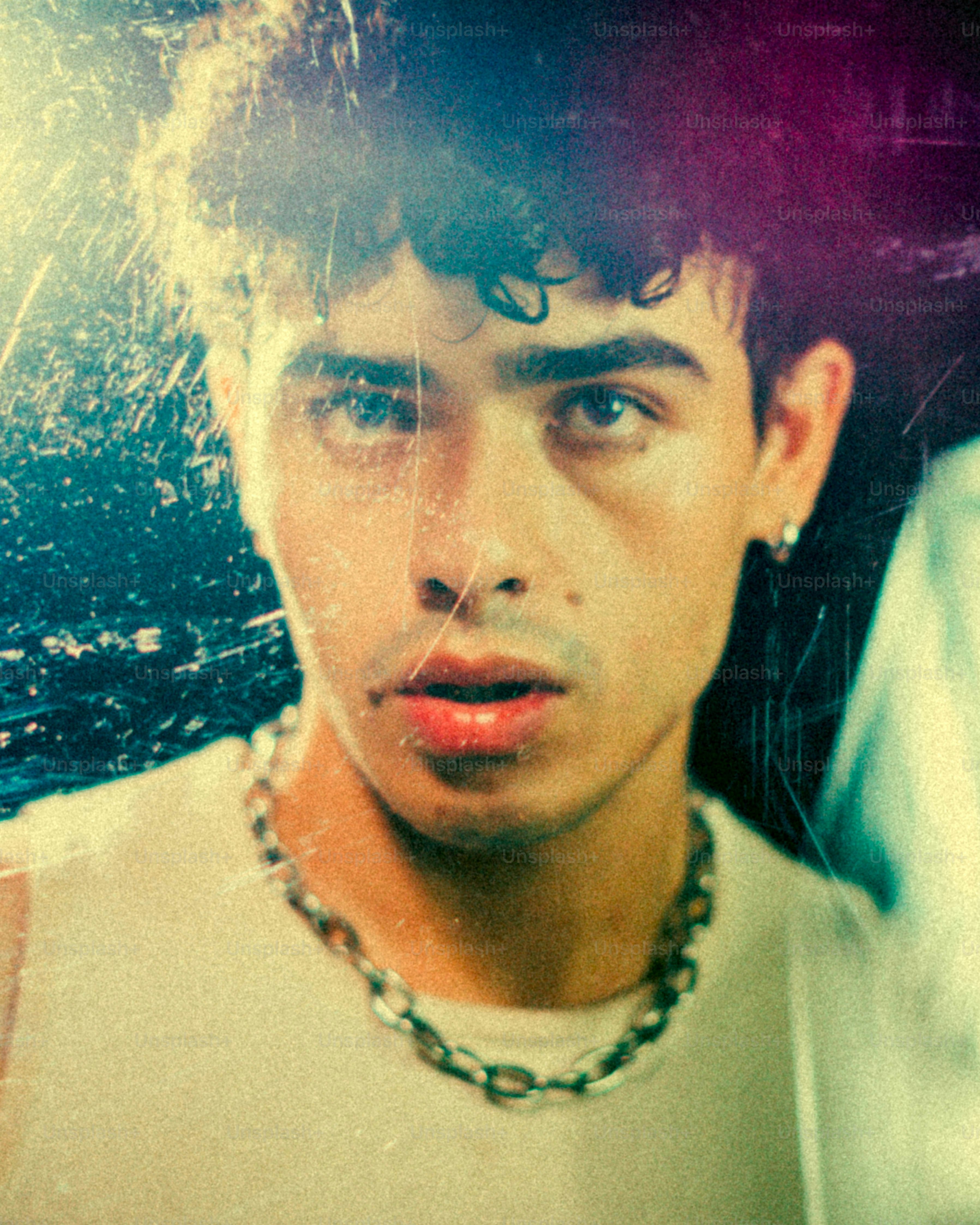 Homem novo com cabelo encaracolado e colar chain