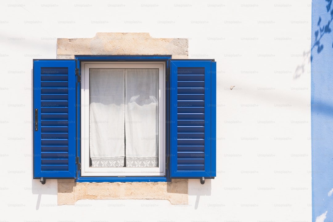 White window with open blue shutters on wall