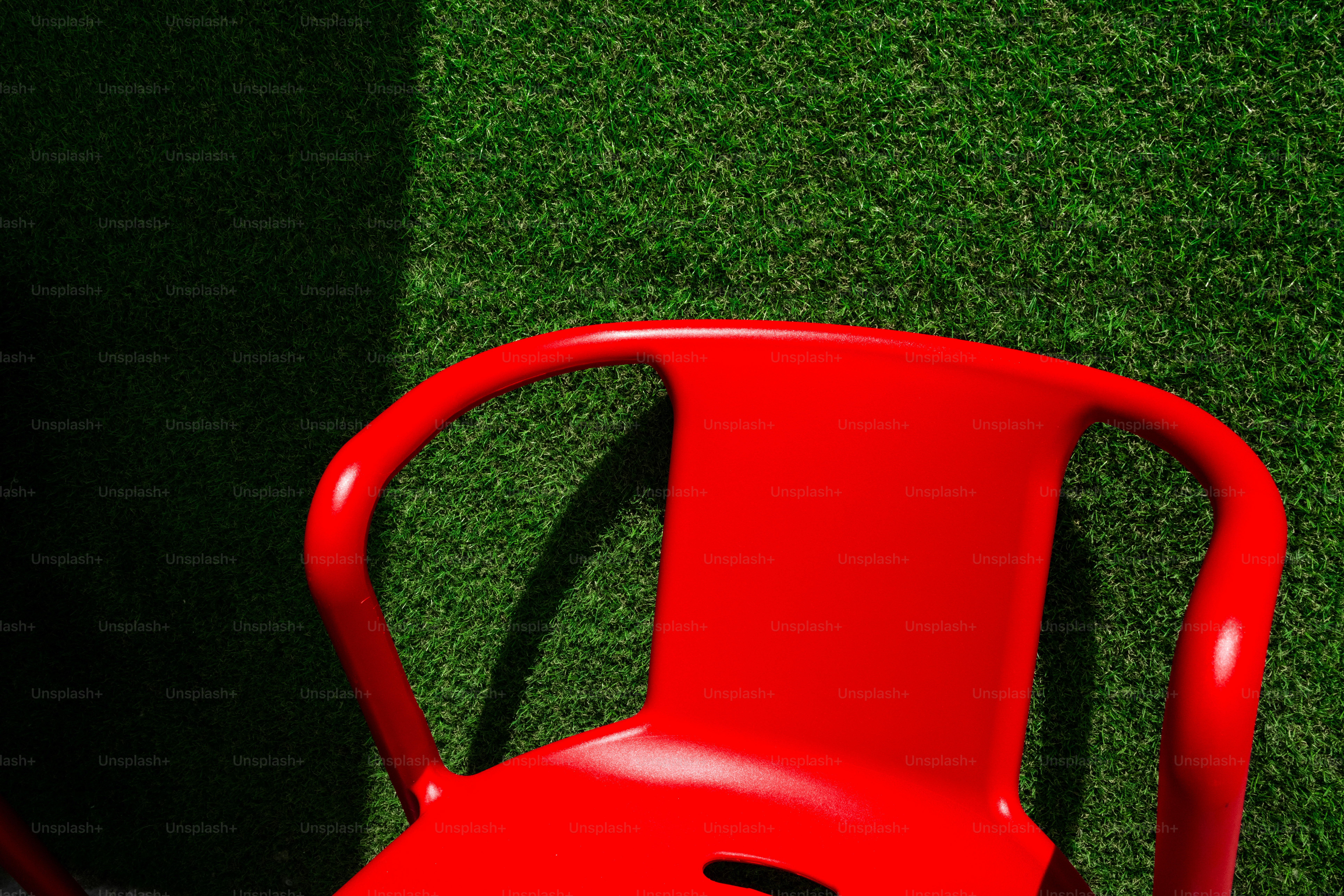 A bright red chair sits on green grass
