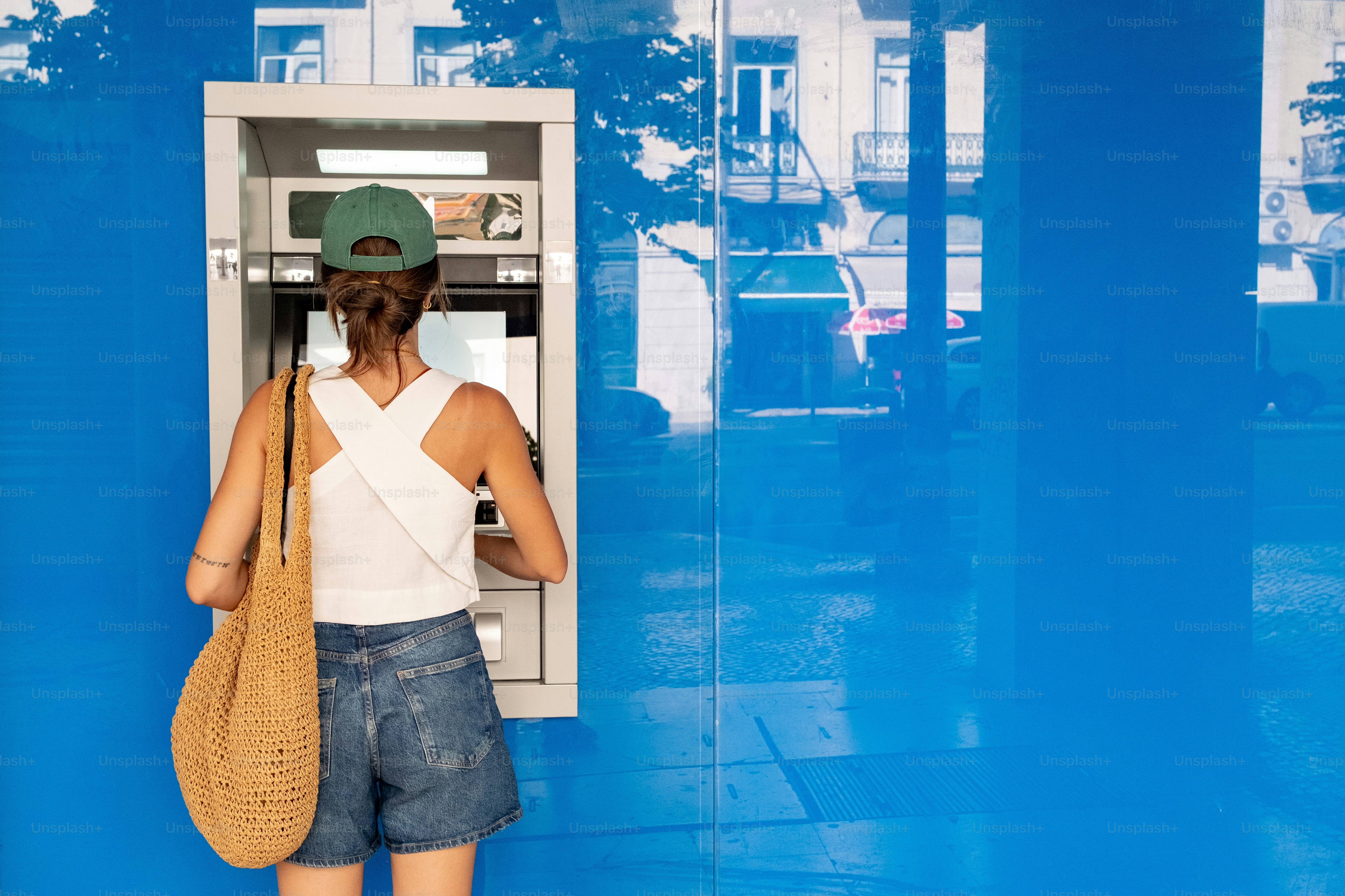 Woman using an atm on a blue wall photo – Money Image on Unsplash