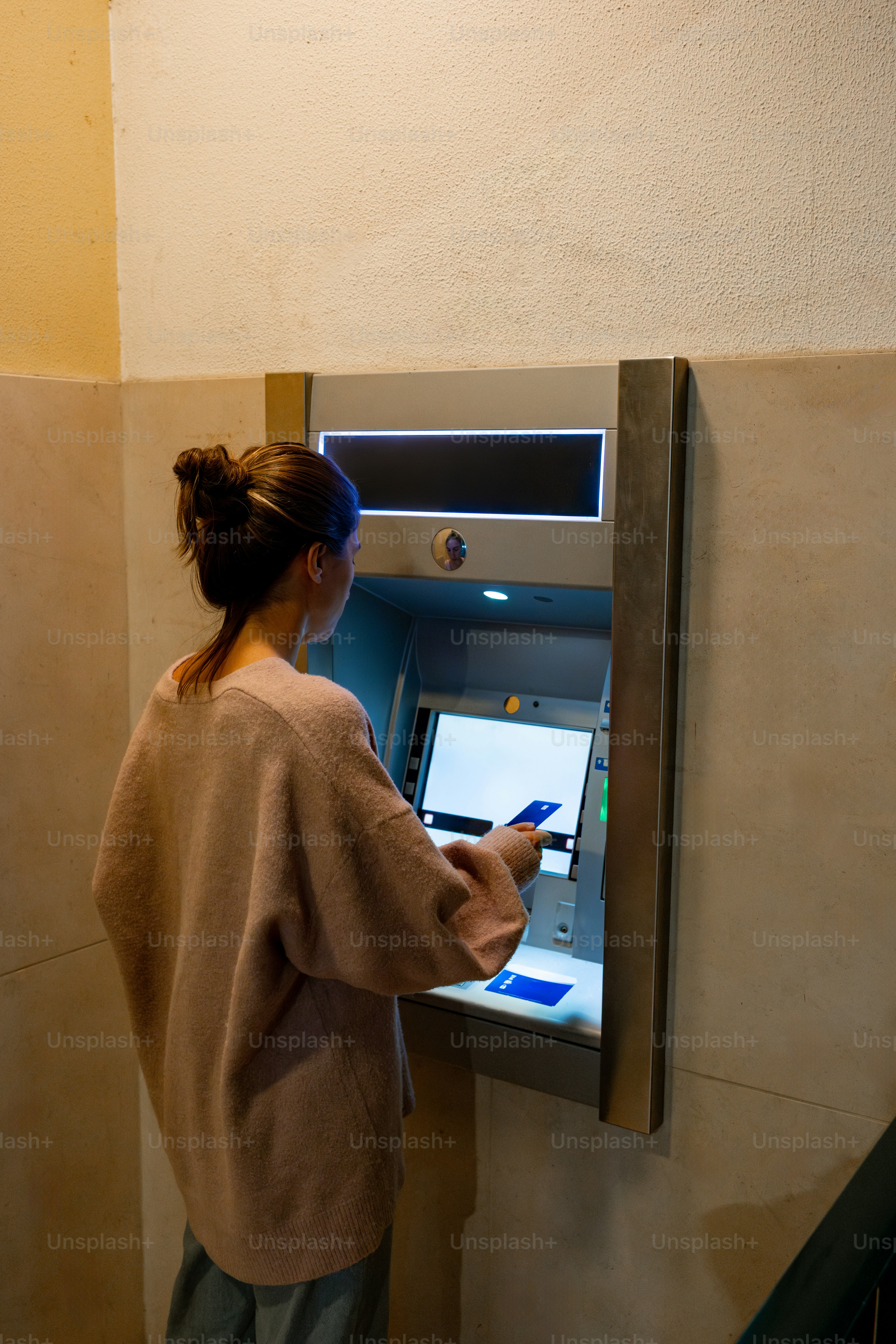 Woman using an atm on a blue wall photo – Money Image on Unsplash