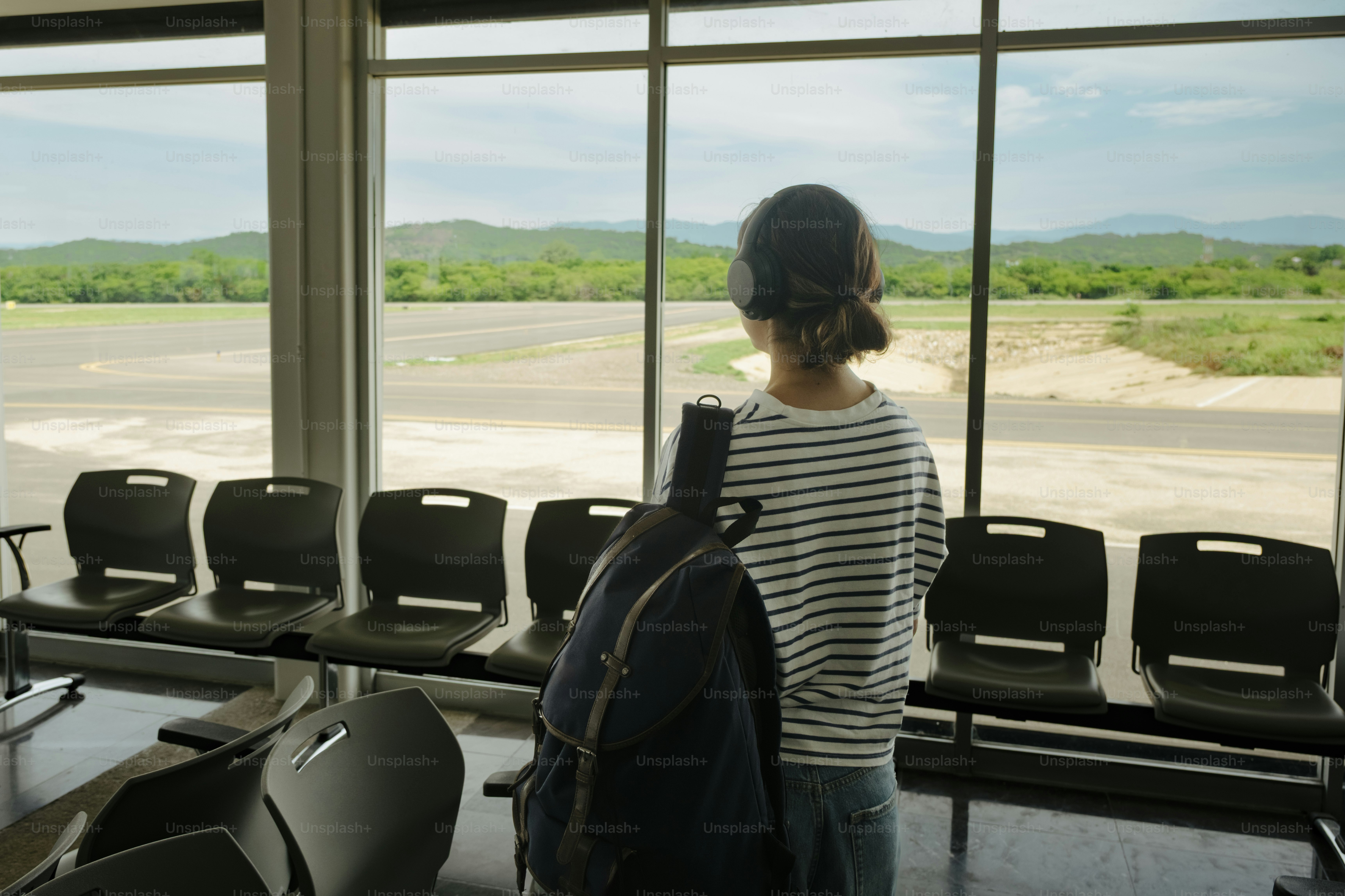 Person looking out airport window at tarmac