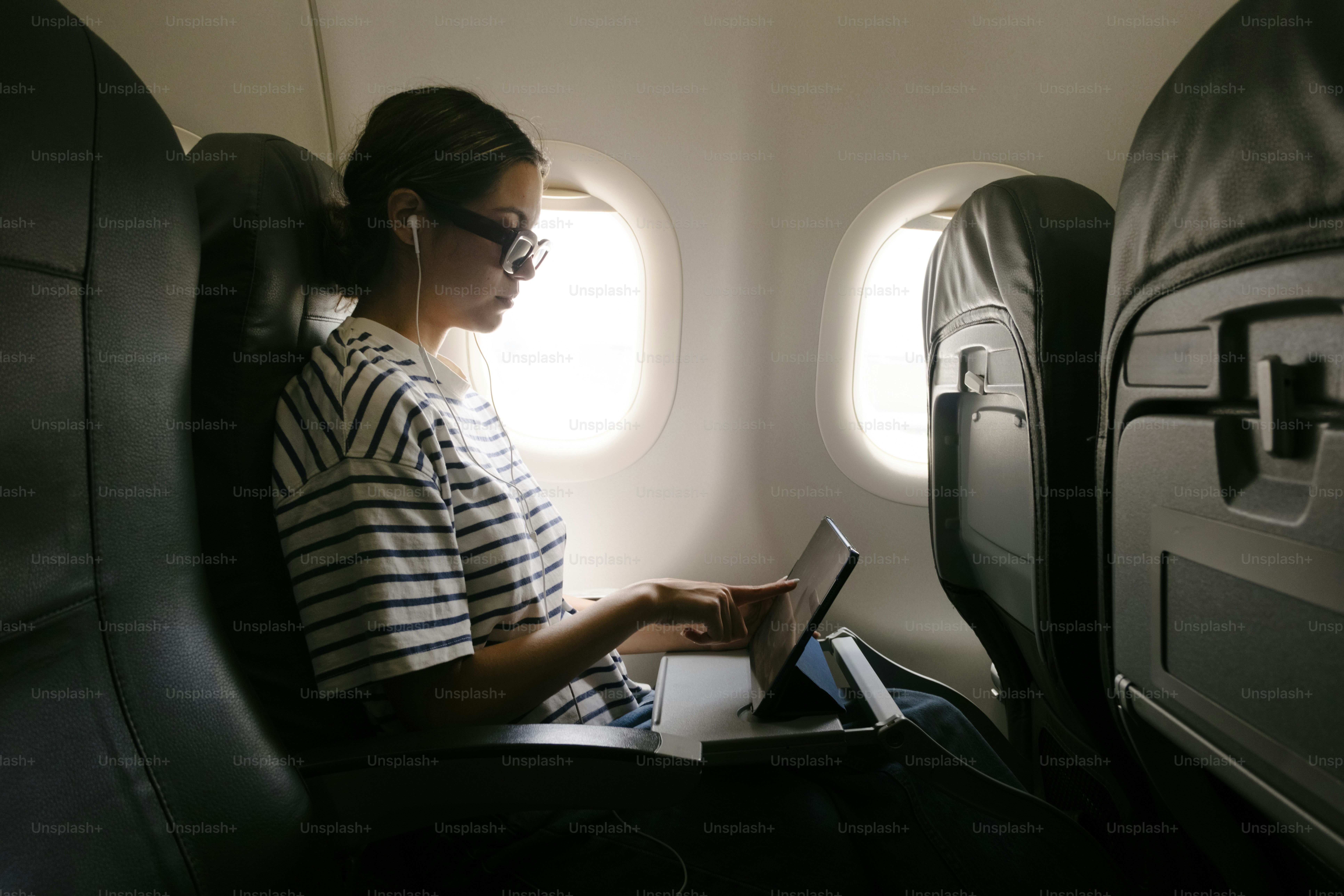 Woman working on laptop inside airplane cabin