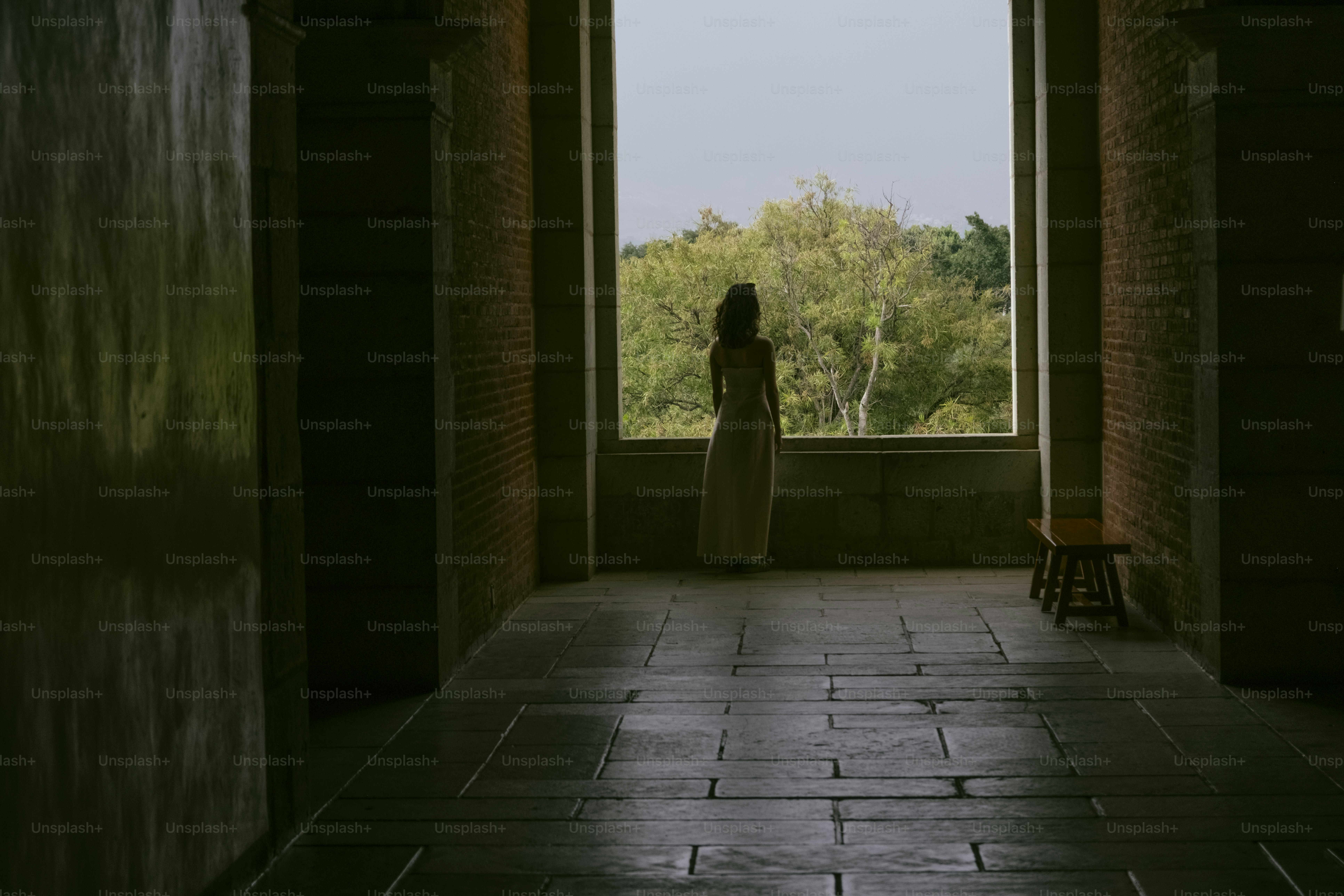 Frau, die aus einem großen Fenster auf die Landschaft schaut