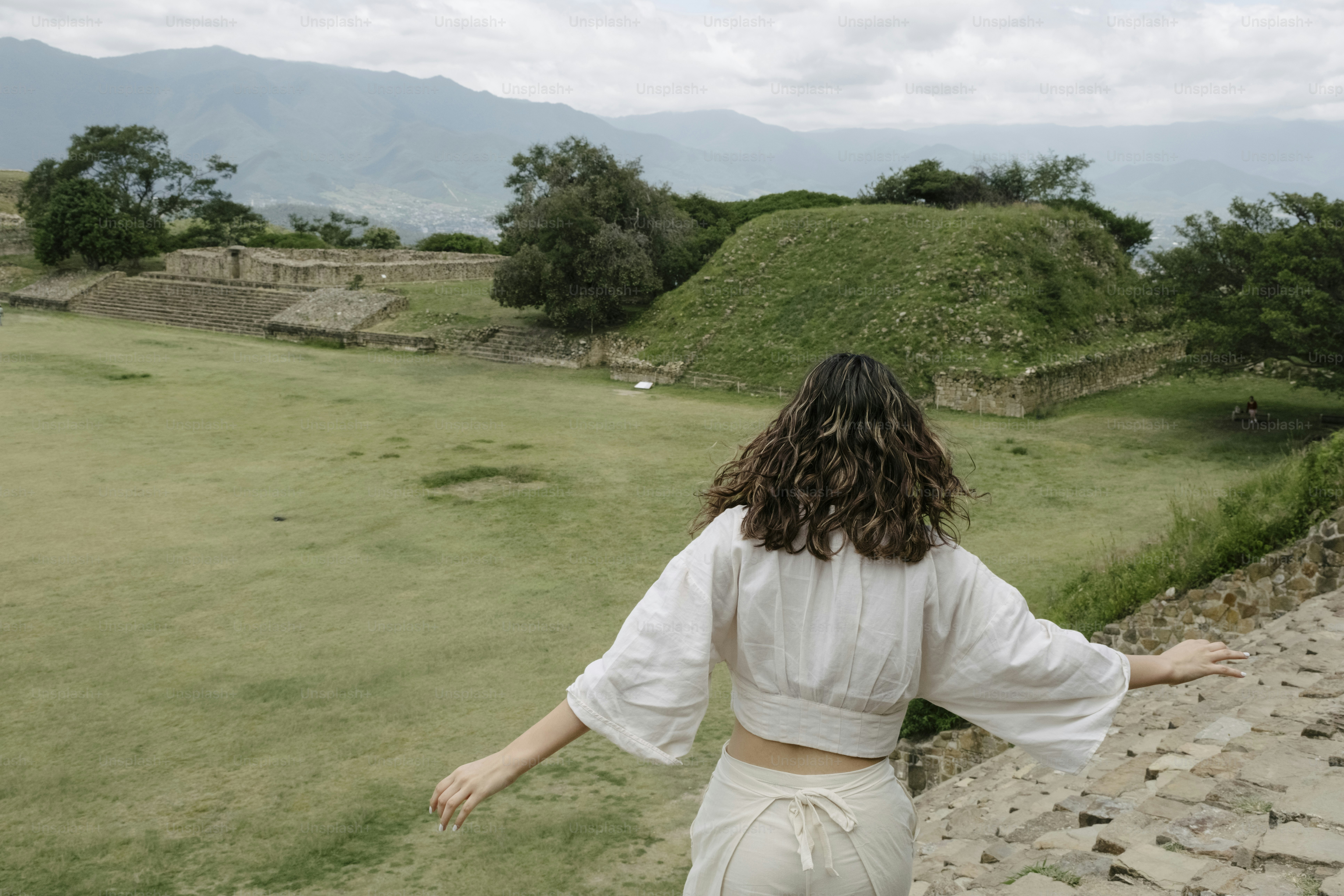 Frau in weißem Kleid geht auf antike Ruinen zu