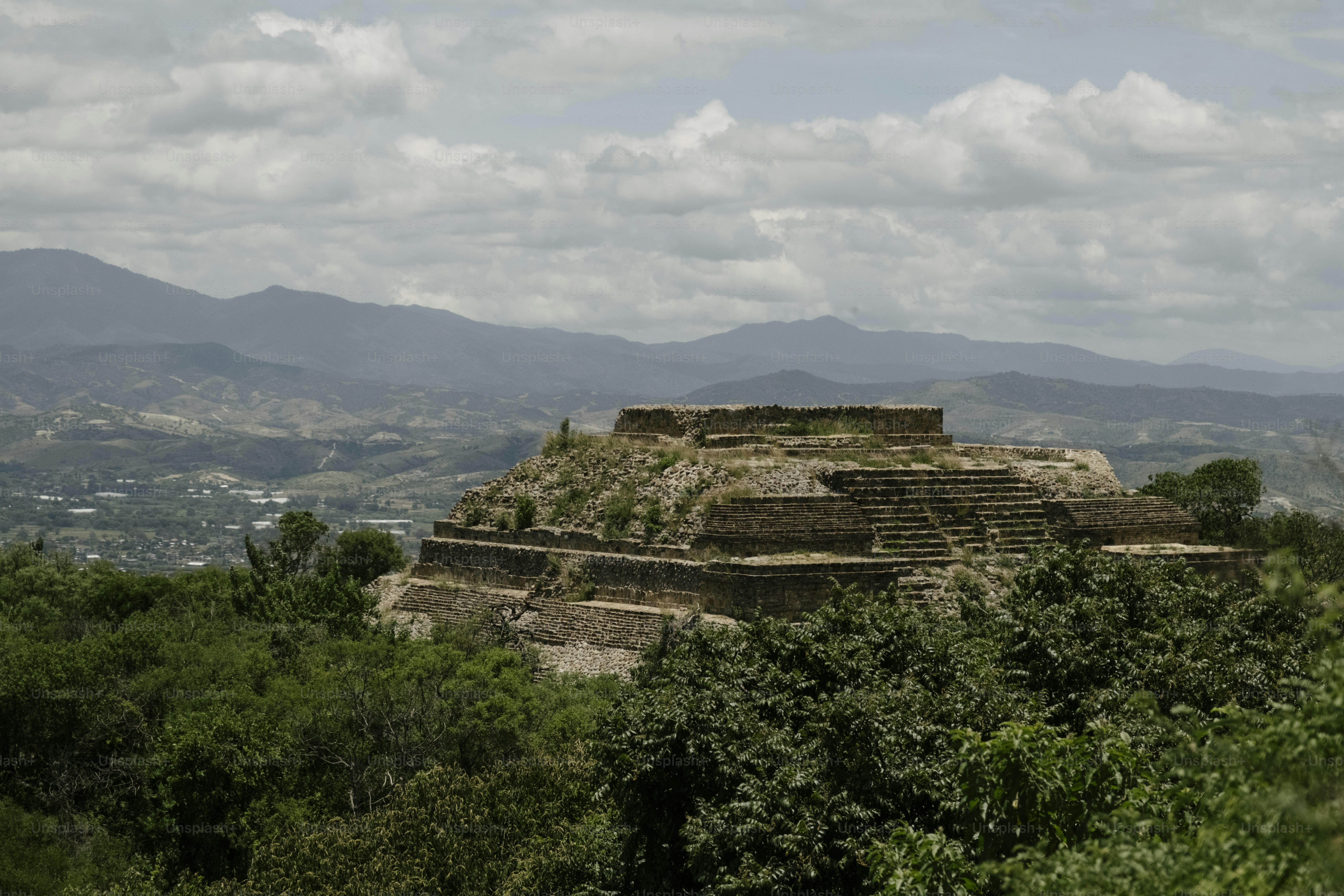 Ancient ruins atop a lush green hill under clouds