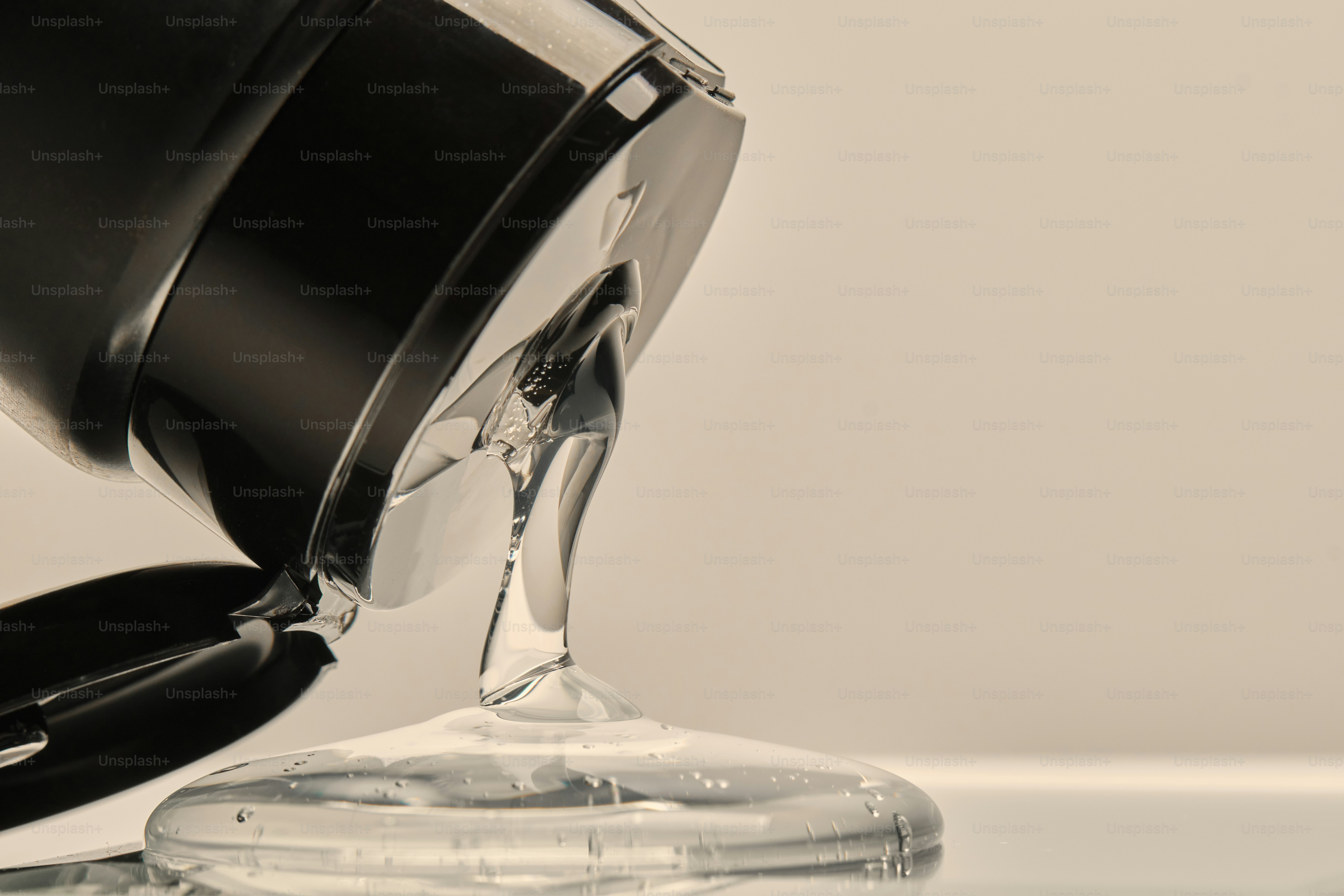 Clear liquid pouring from a black bottle onto surface photo – Green ...