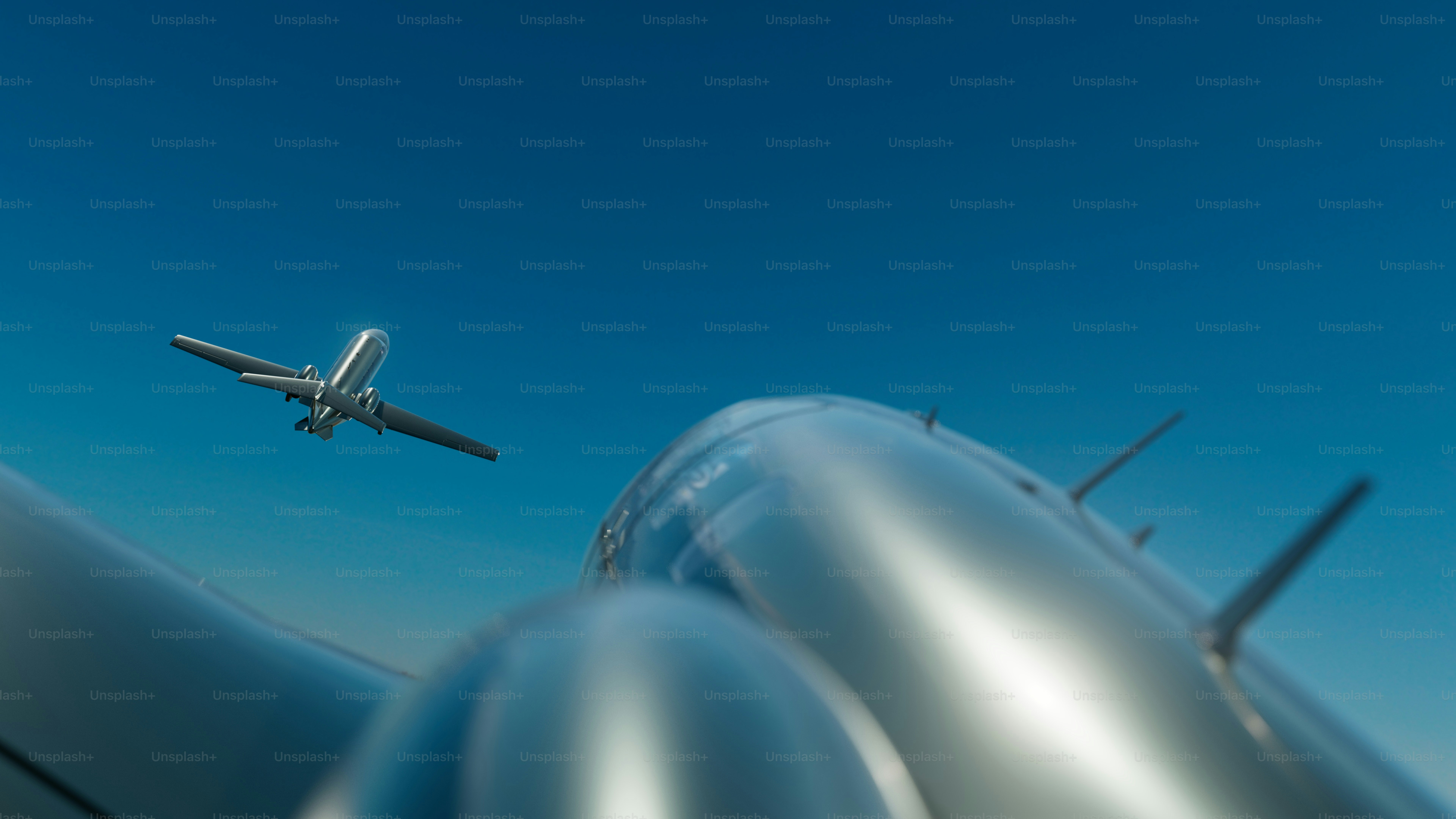 A private jet flies overhead against a deep blue sky, captured from the perspective of another aircraft in flight.