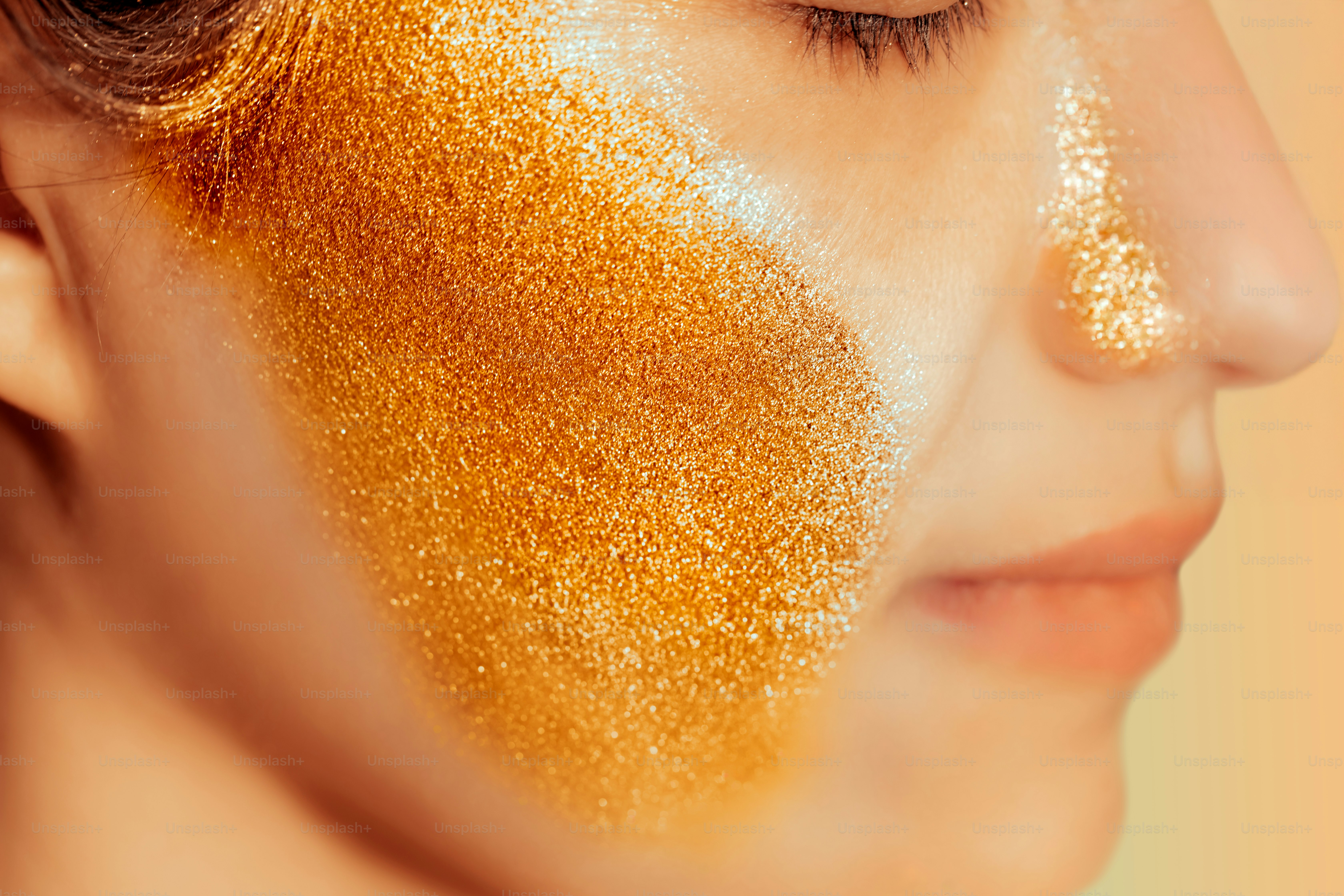 Woman's face covered in sparkling gold glitter.