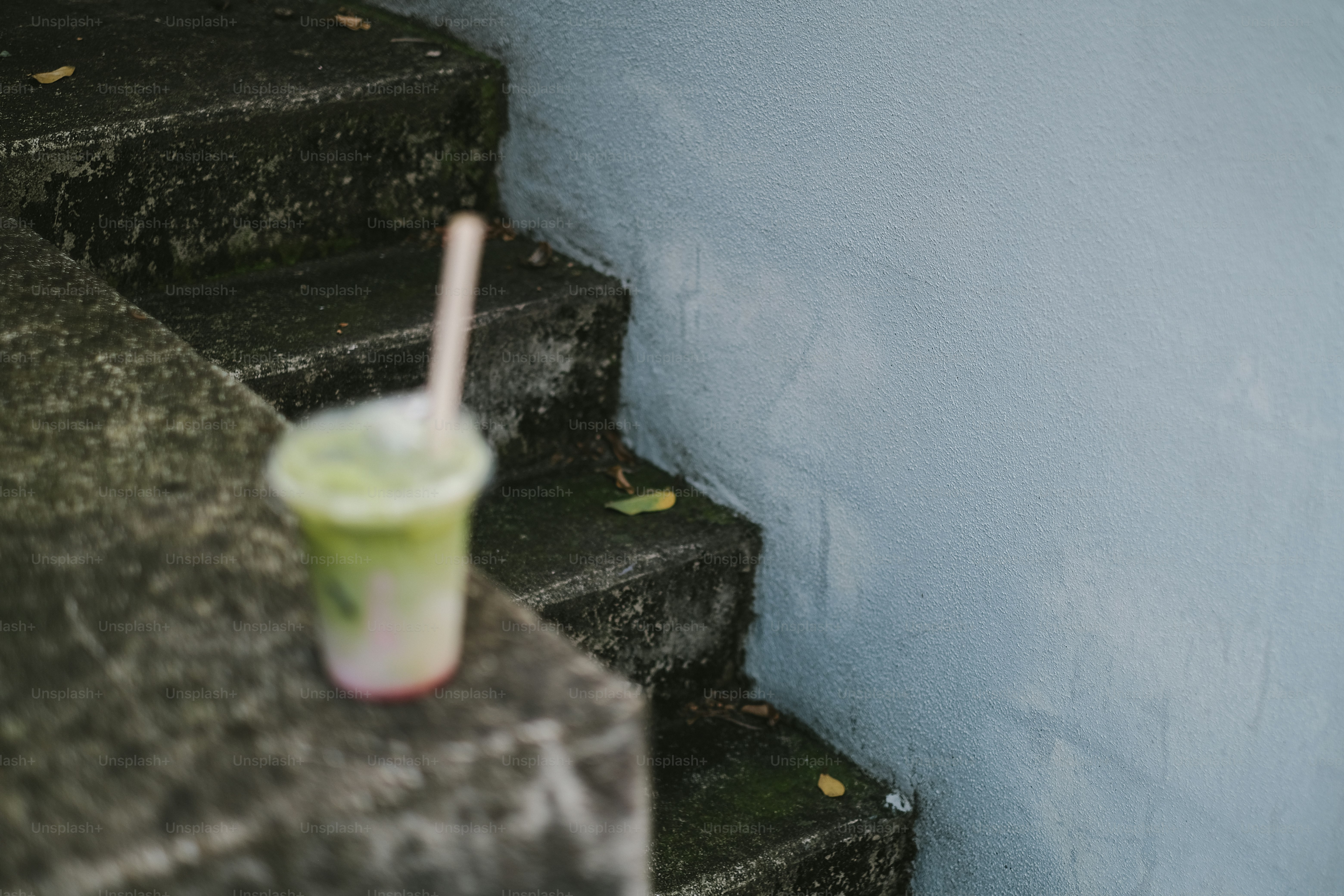 階段でストローで飲み物を飲む