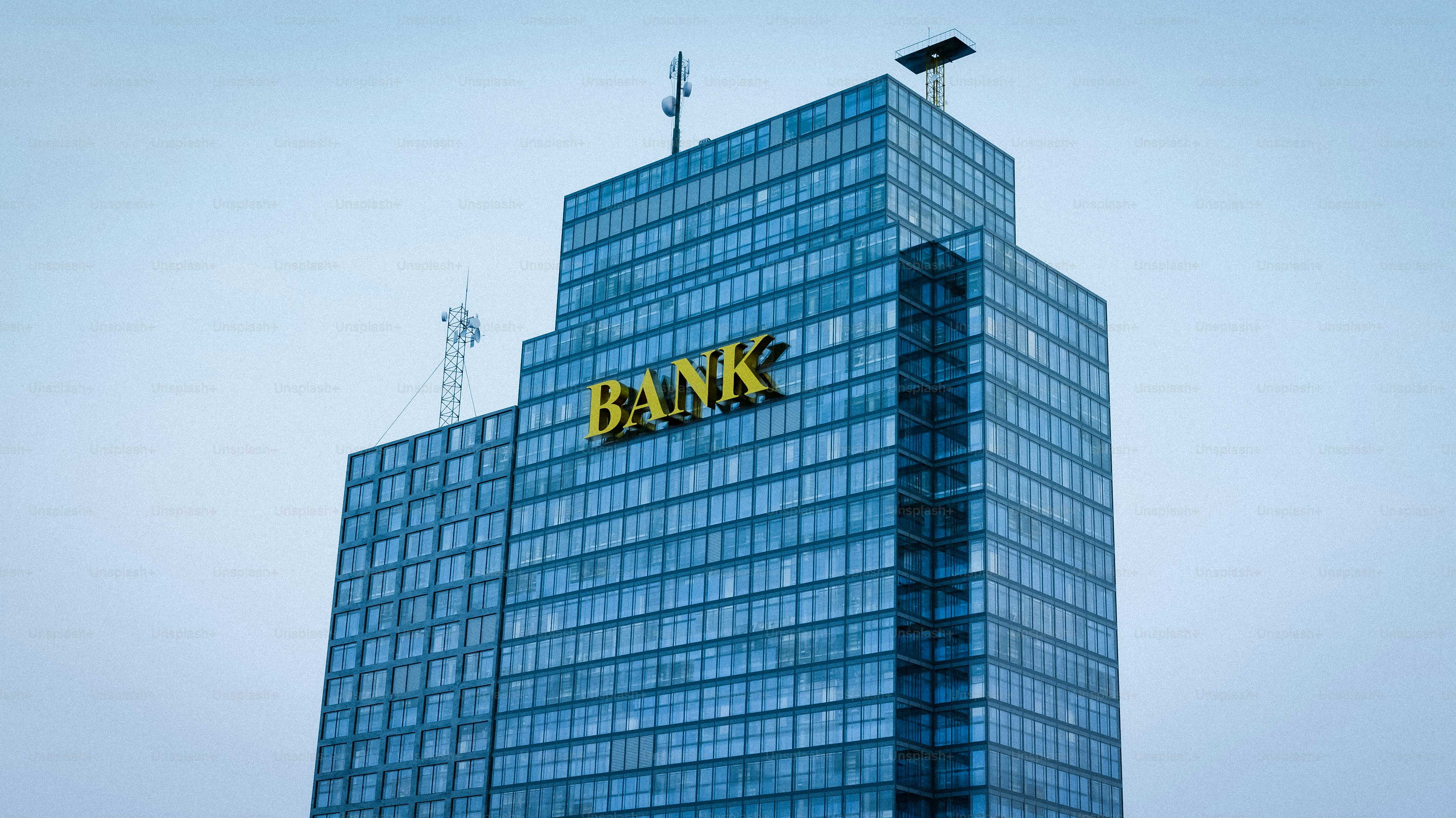 Modern glass skyscraper with yellow logo against sky