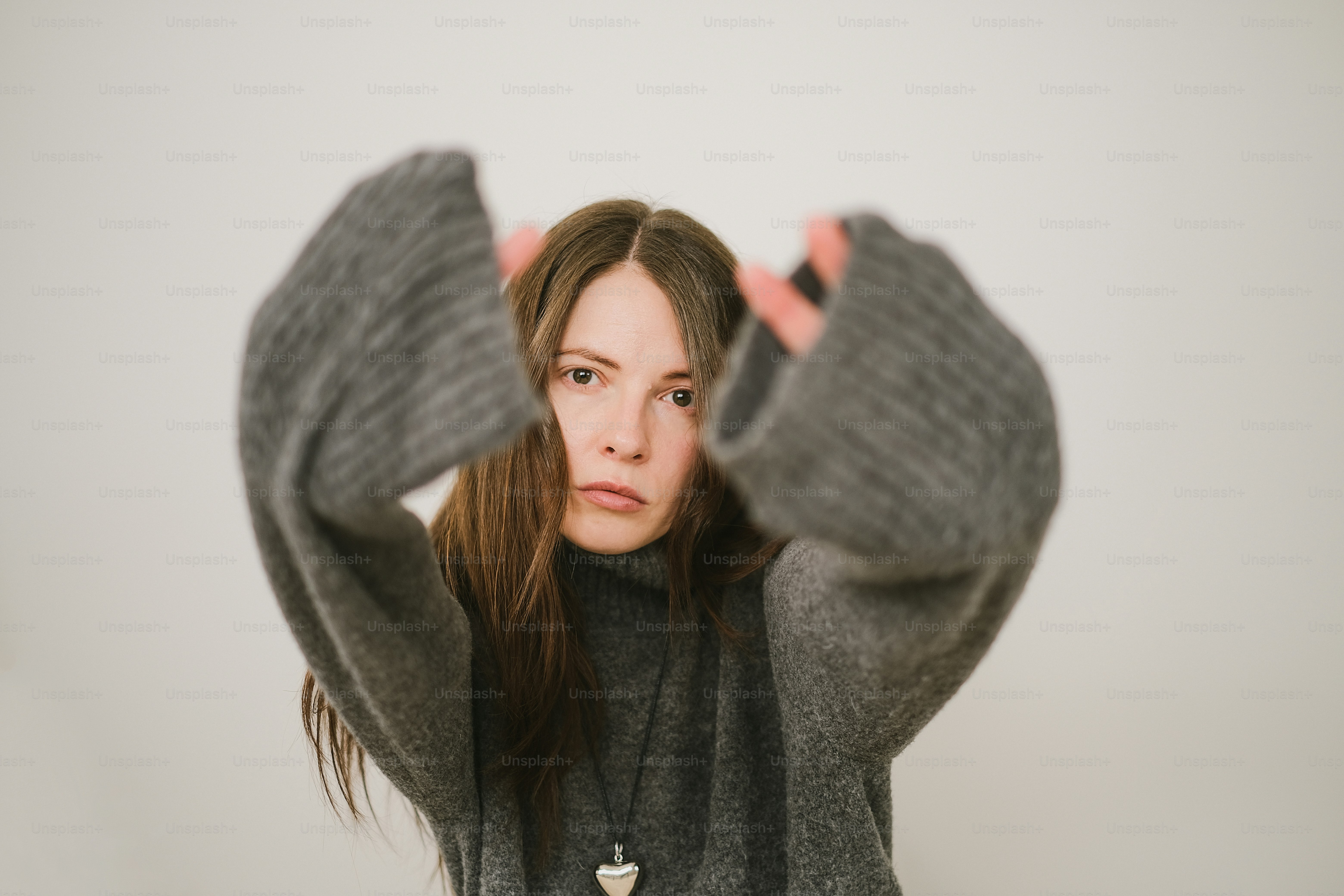 腕を上げたグレーのセーターを着た女性