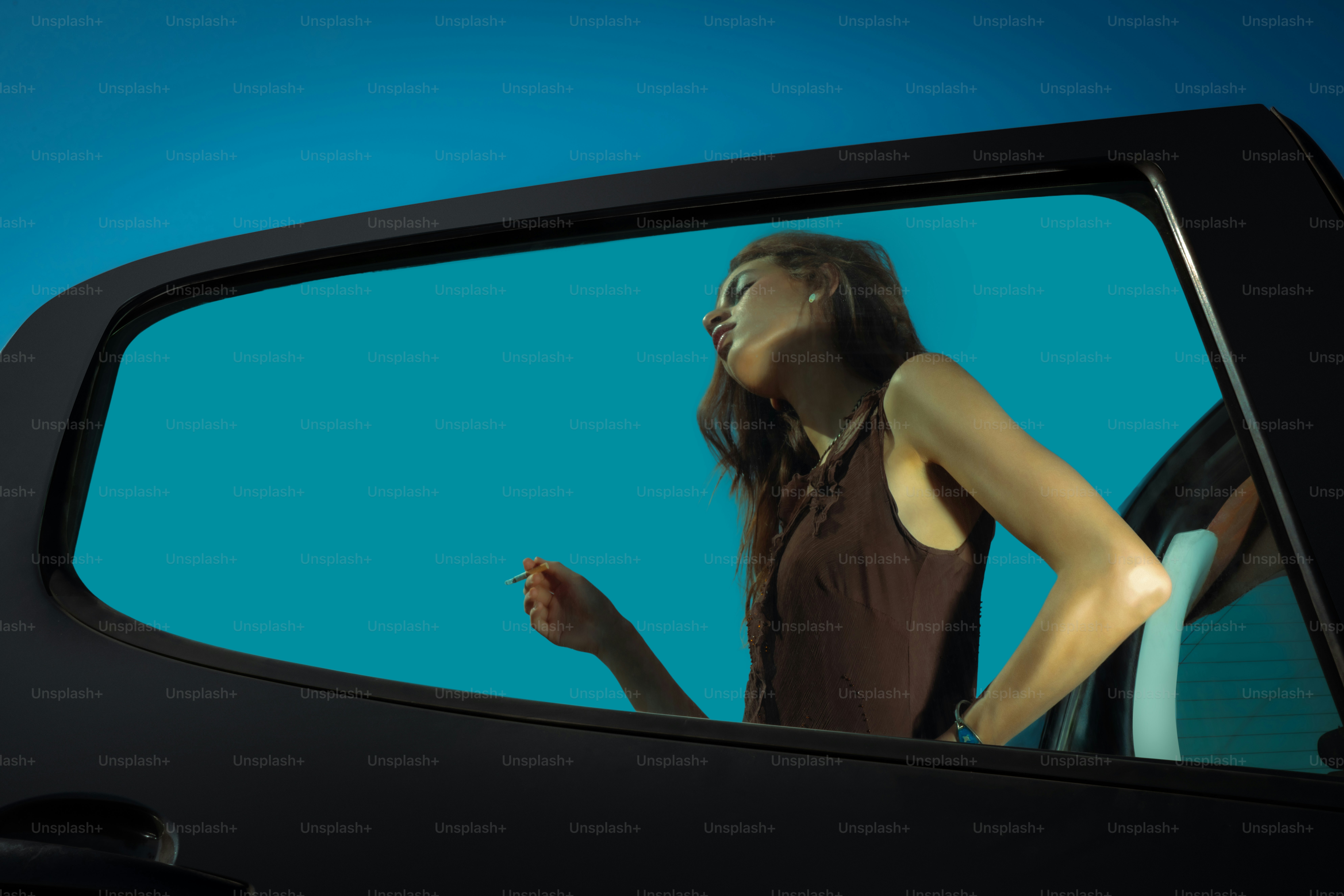 Mujer asomada por la ventanilla del coche contra el cielo azul