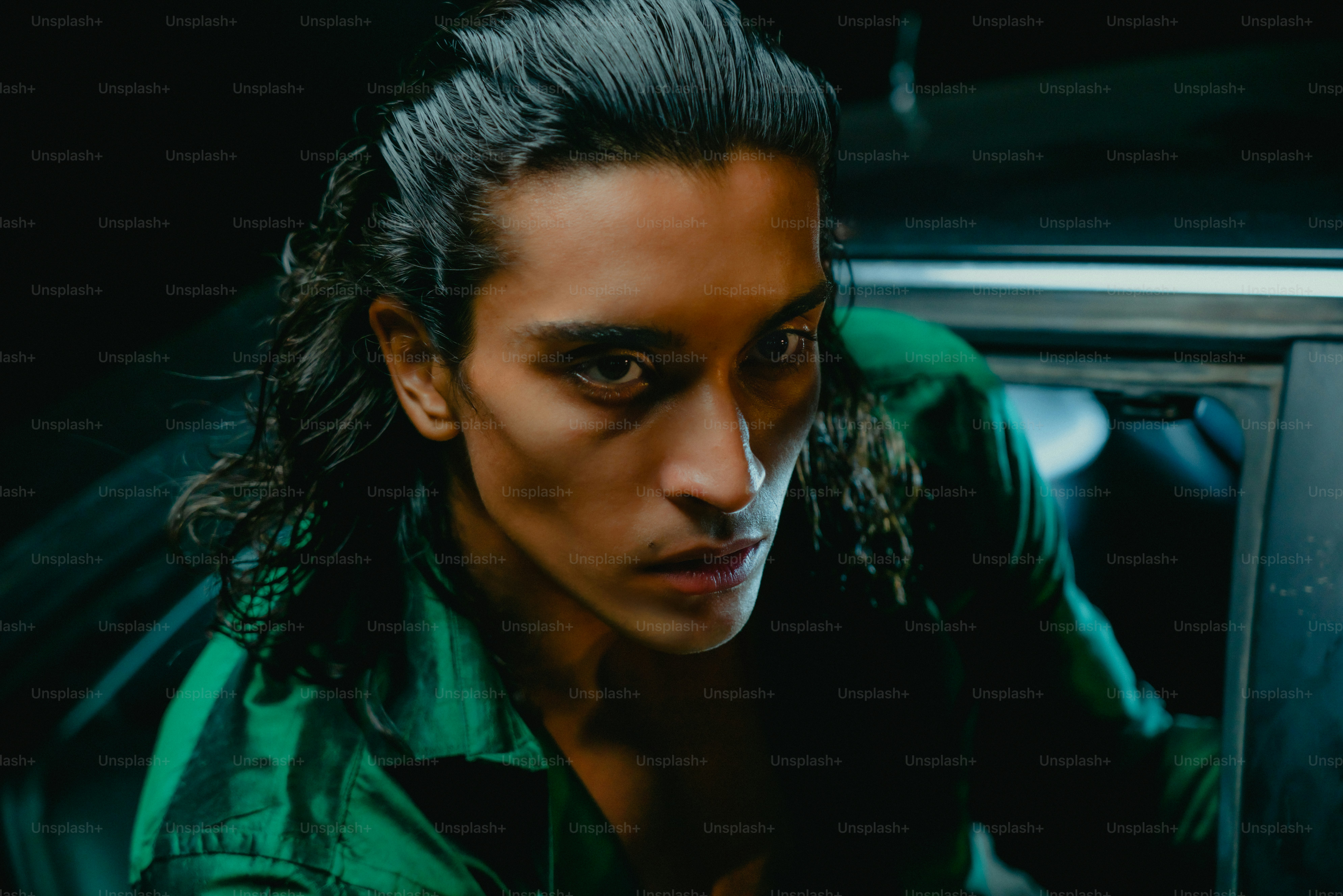 Hombre con cabello largo y oscuro se inclina hacia el auto