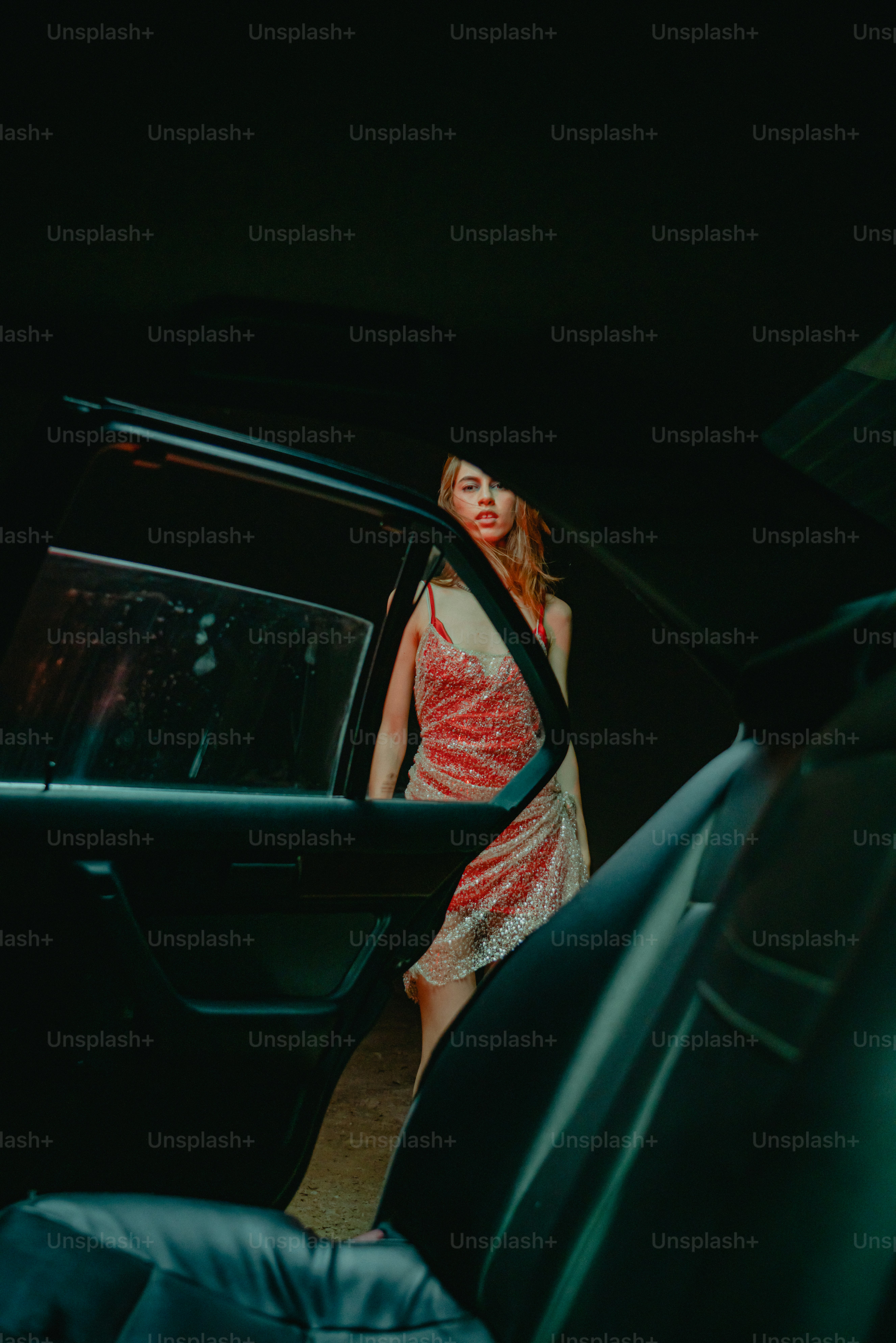 Mujer con vestido brillante saliendo de un coche por la noche