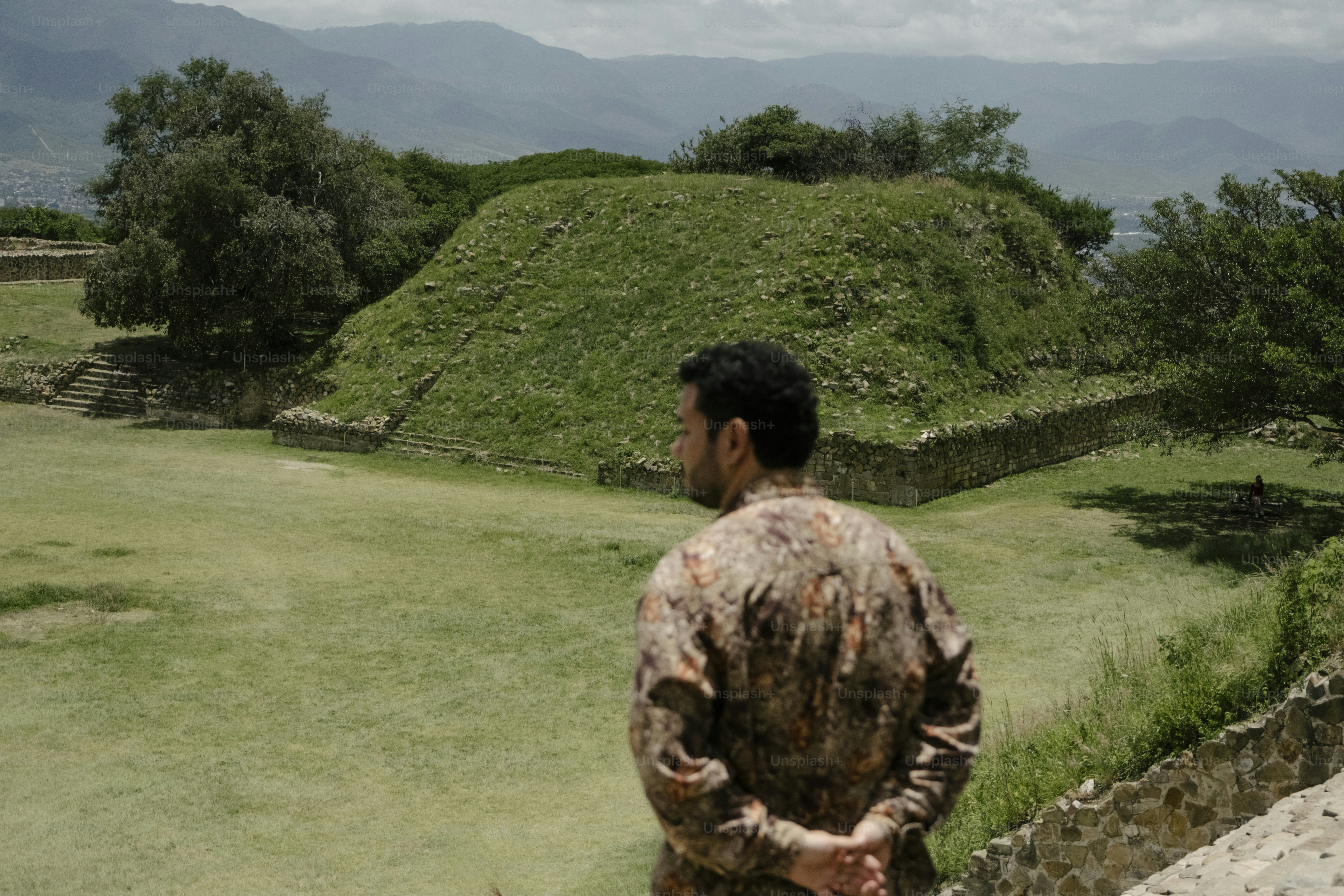 Man looking at ancient ruins with green hills