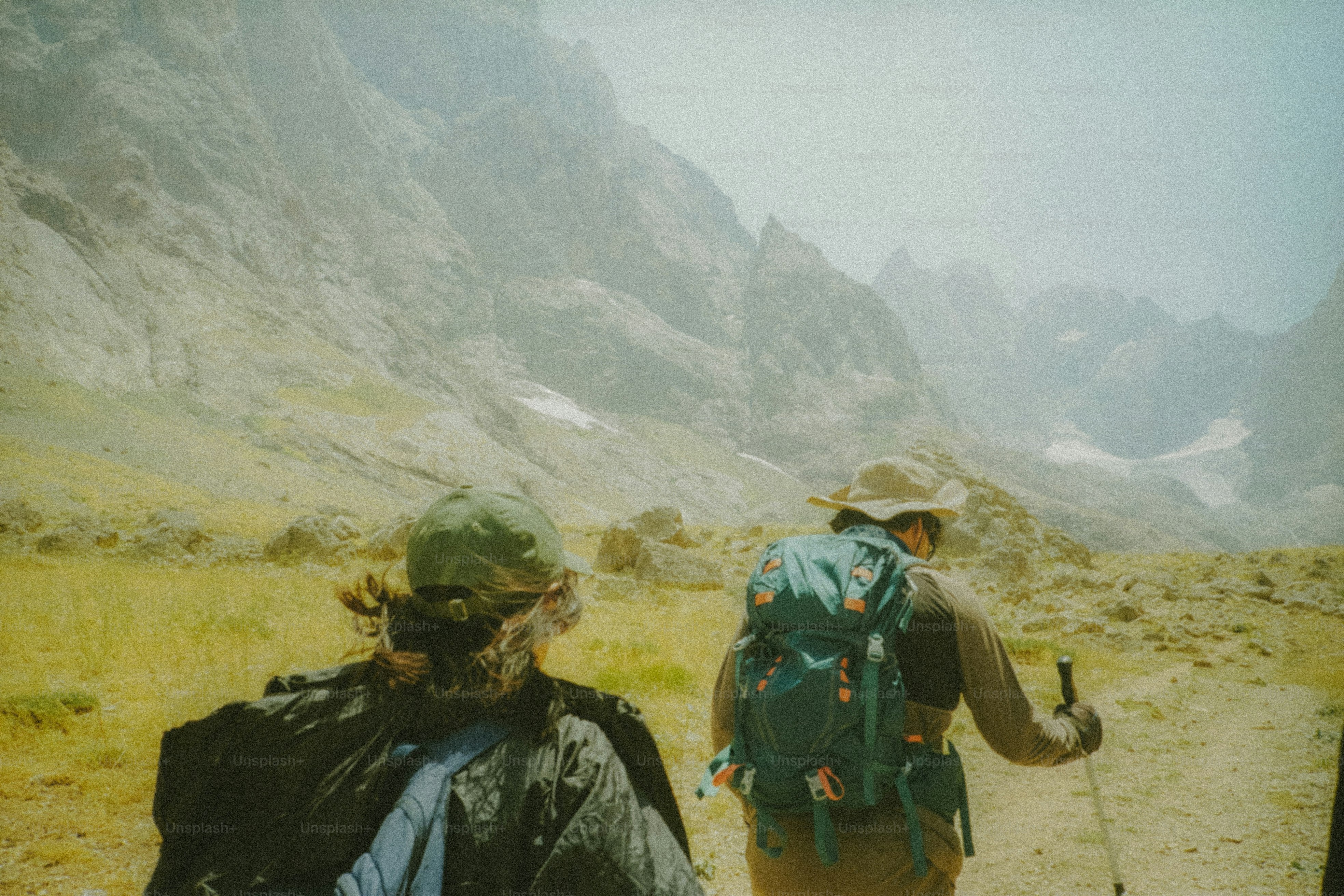 Two hikers walk toward majestic mountains