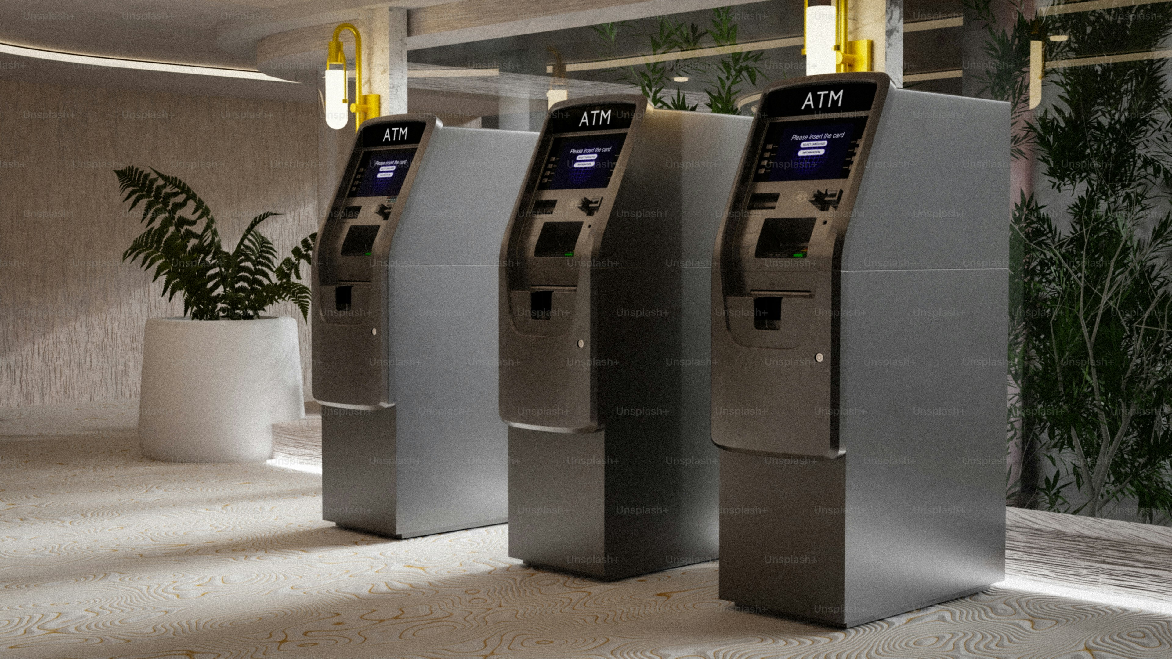 Tre bancomat moderni allineati in un interno pulito.