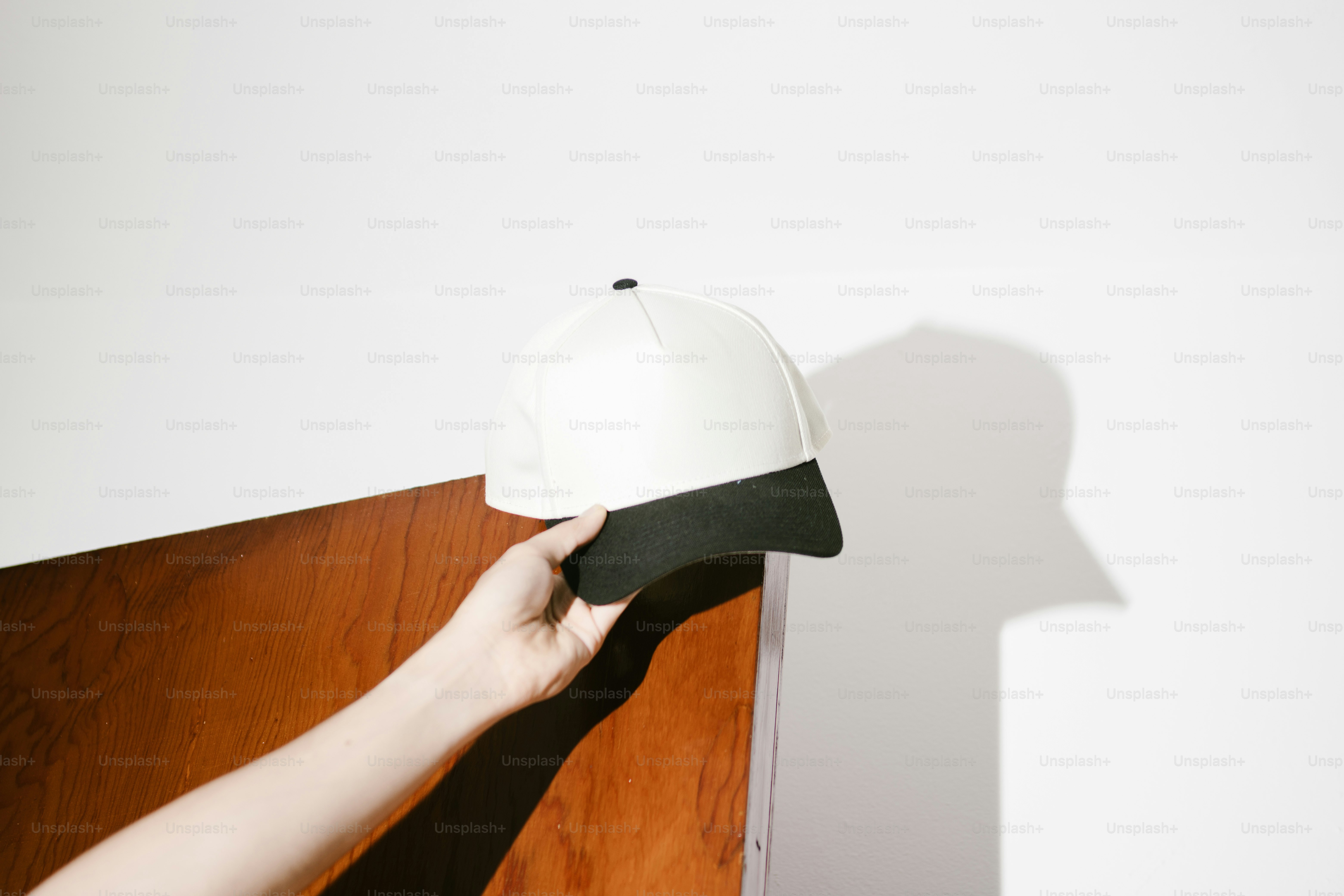 Main tenant une casquette de baseball blanche et noire
